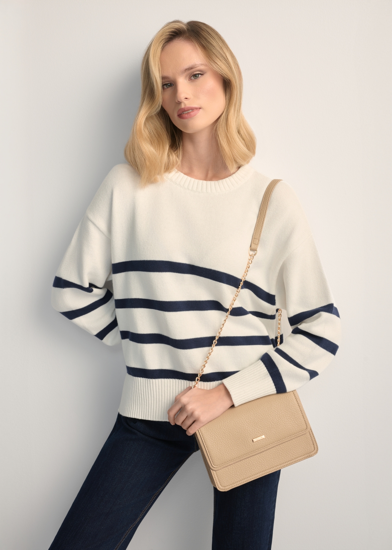 Malá béžová dámska kabelka TOREC-1015-1B(W26), pohľad spredu na produkt na modelke, viditeľná polovica siluety.