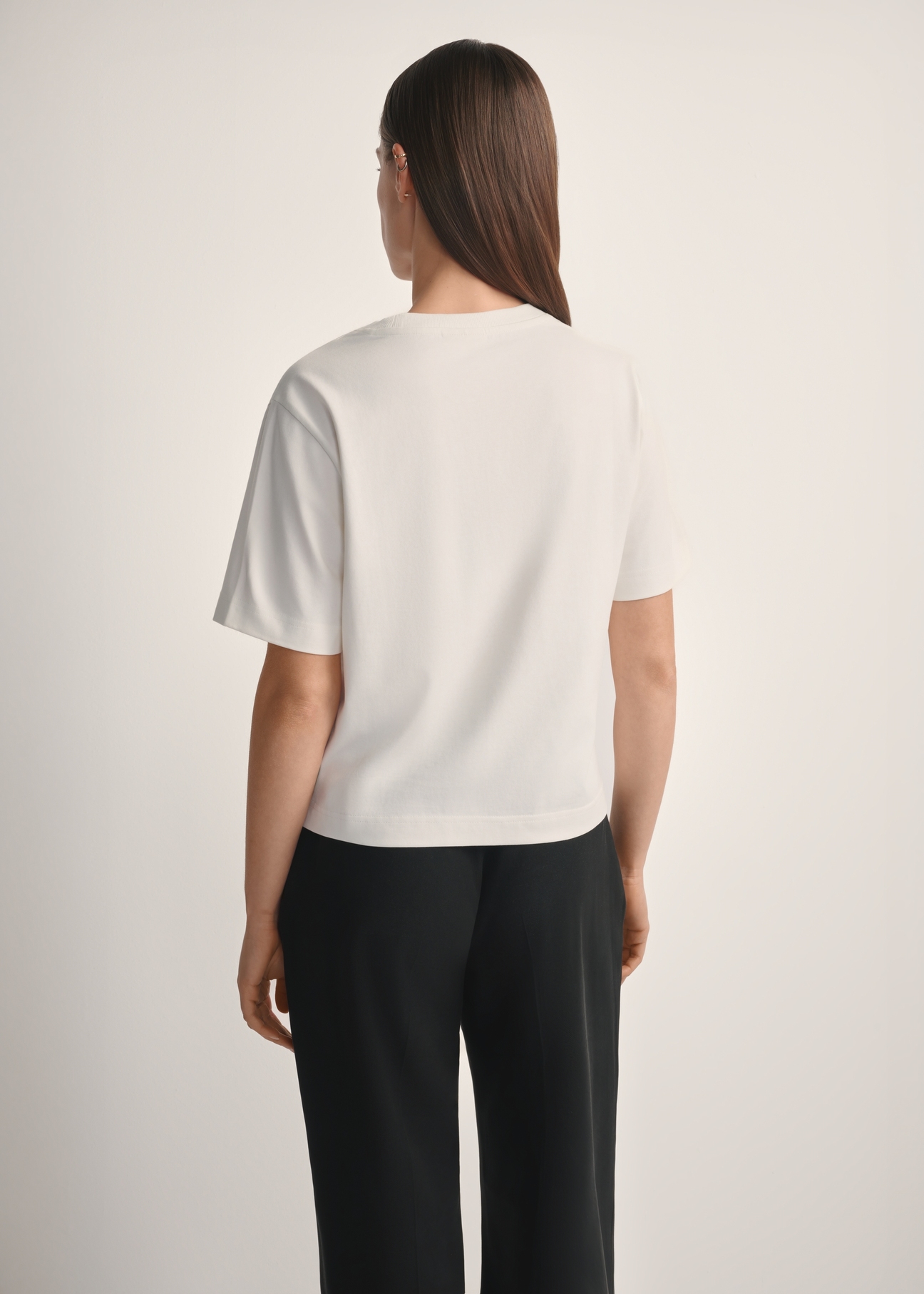 Dámske krémové bavlnené tričko TSHDT-0138-0B(W26), pohľad na produkt zozadu na modelke, viditeľná polovica siluety.