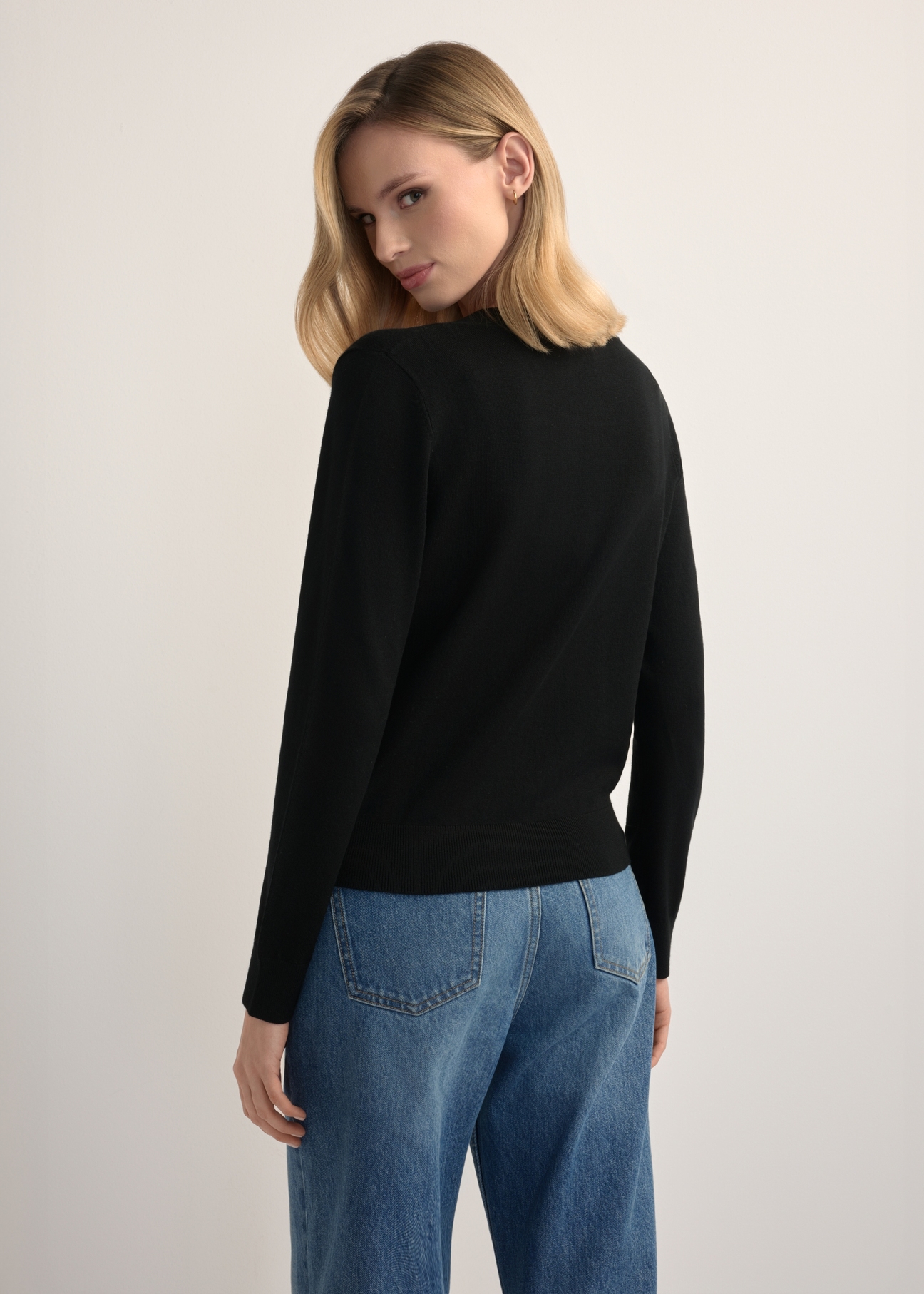 Čierny dámsky kardigan KARDT-0061-99(W26), pohľad na modelku zozadu. Viditeľná polovica siluety.