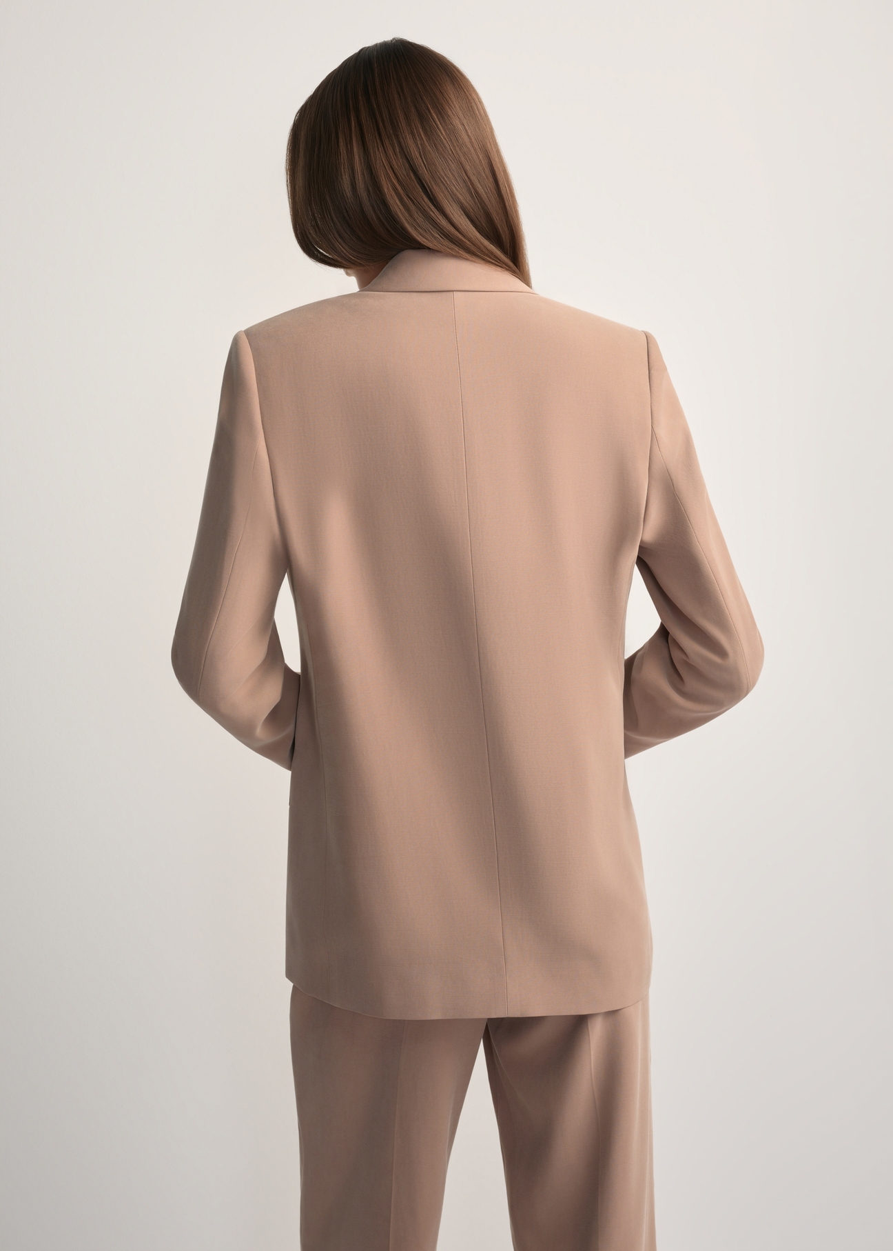 Dámske sako ťavej farby ZAKDT-0031A-1D(W26) - pohľad na výrobok zozadu, na modelke, na svetlom pozadí. Viditeľná polovica siluety.