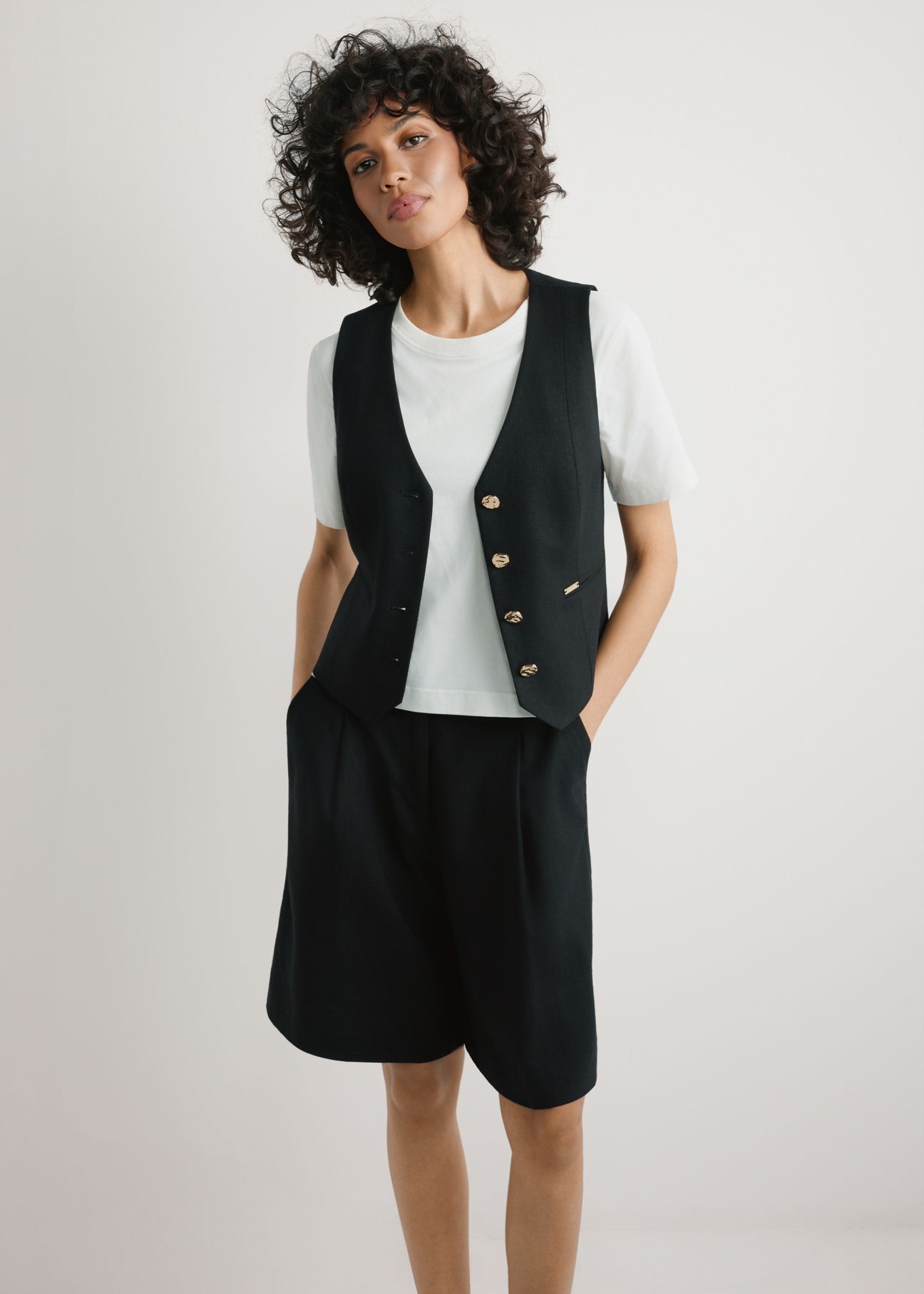 Čierna vesta z viskózy a ľanu KAMDT-0038-99(W26) - pohľad spredu na produkt, na modelke, na svetlom pozadí, viditeľná silueta po kolená.