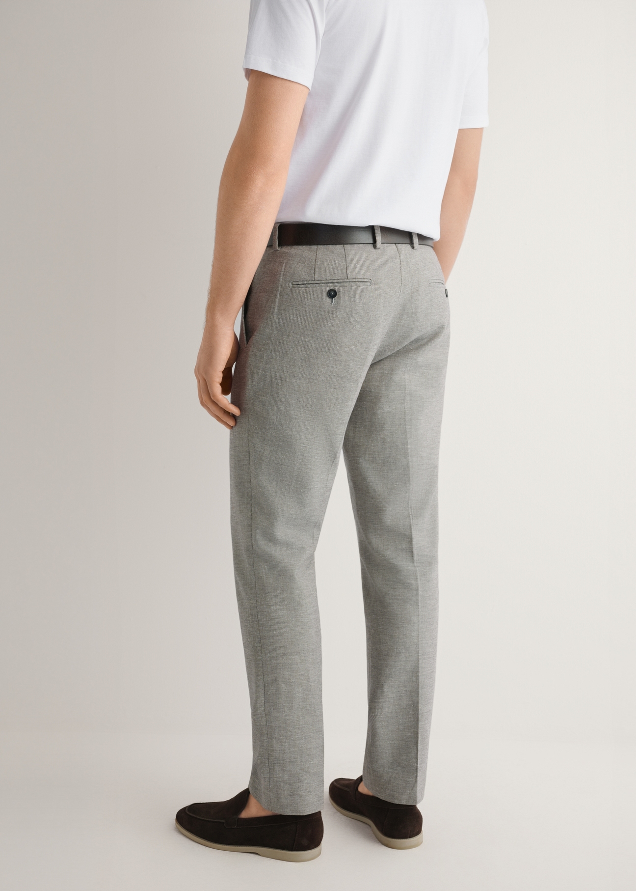 Béžové pánske oblekové nohavice SPOMT-0098-1B(W26), pohľad na produkt zozadu na modelke. Viditeľná polovica siluety.