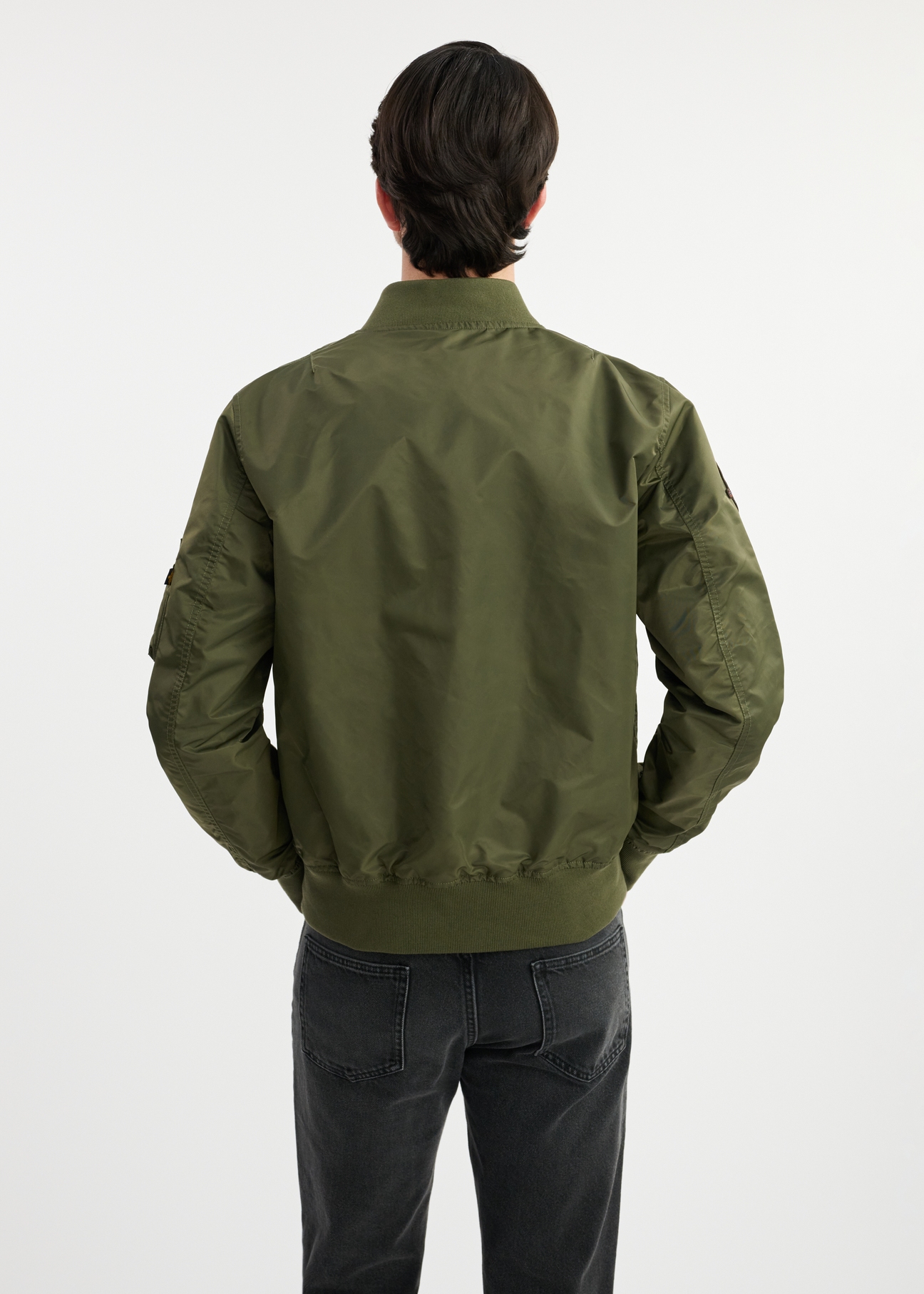 Pánska olivovozelená bomber bunda TOP GUN KURMT-0381-57(W25) - pohľad zozadu na modelku na bielom pozadí. Viditeľná je polovica siluety.