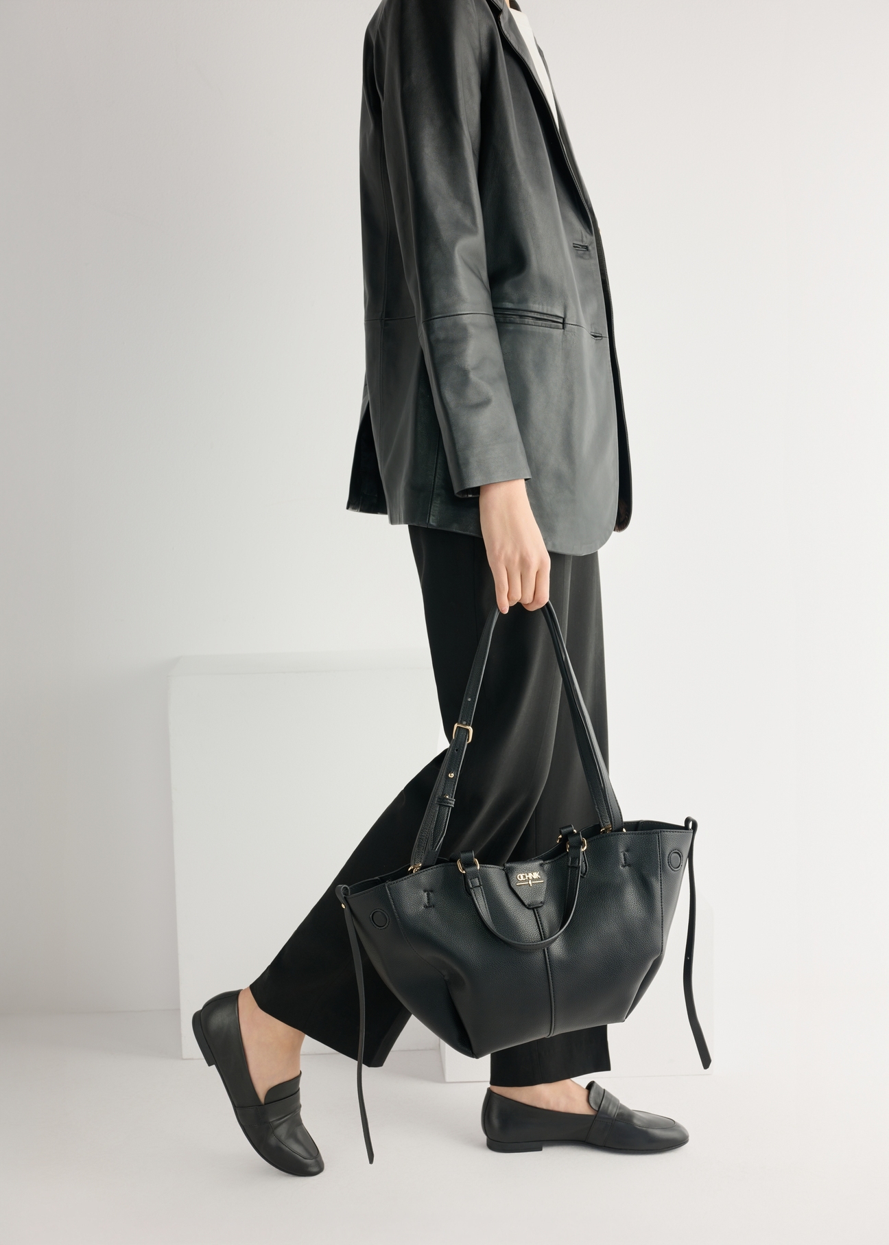 Dámske čierne kožené mokasíny BUTYD-1074A-99(W26), pohľad na produkt spredu na modelke, viditeľná polovica siluety.