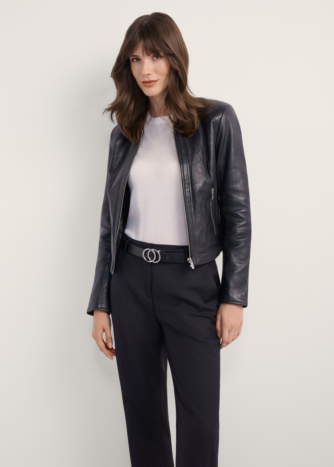 Dámska čierna krátka kožená bunda KURDS-0294-99(KS), pohľad spredu na produkt na modelke. Viditeľná polovica siluety.