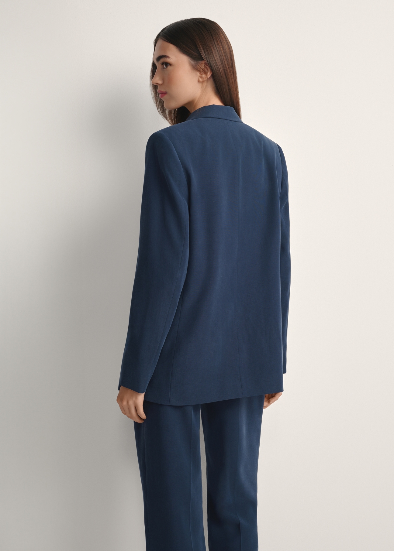 Dámske tmavomodré sako ZAKDT-0031A-7E(W26), pohľad na modelku zozadu. Viditeľná polovica siluety.