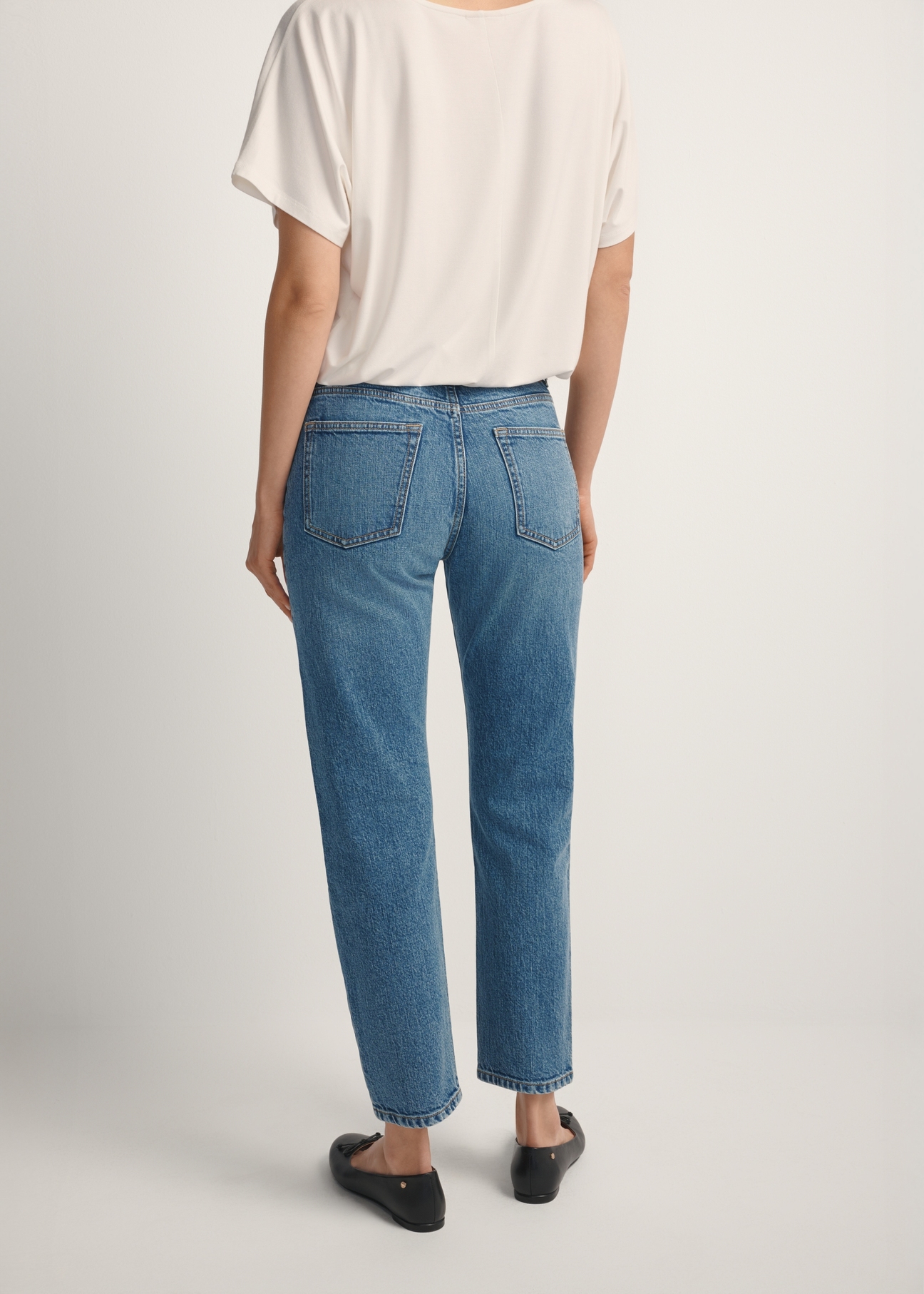 Dámske tmavomodré džínsy JEADT-0011-7C(W26), pohľad na modelku zozadu. Viditeľná polovica siluety.