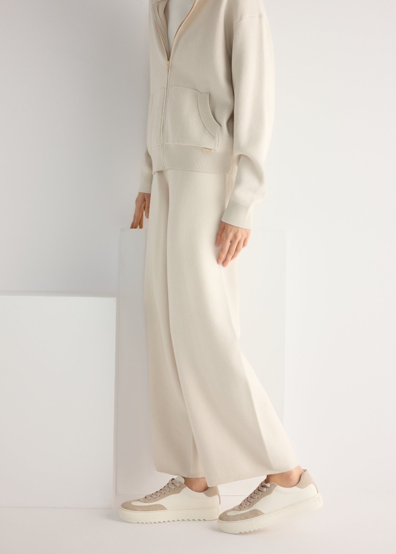 Dámske kožené tenisky krémovej farby BUTYD-1260-0B(W26), pohľad na produkt z boku na modelke, viditeľná polovica siluety.