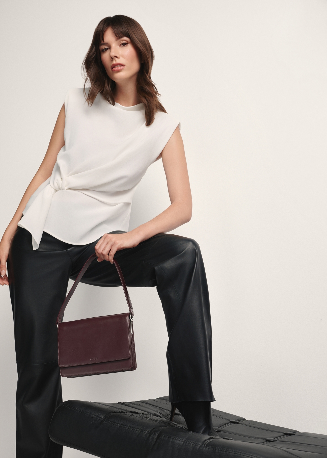 Dámska kožená kabelka v bordovej farbe TORES-1189-49(Z25), pohľad na produkt v ruke modelky na svetlom pozadí.