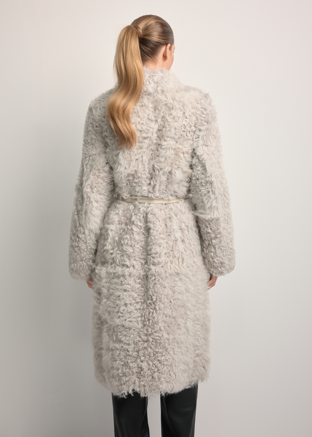 Dámsky obojstranný kabát z ovčej kože v krémovej farbe KOZDS-0091-1394(Z25), pohľad zozadu na modelku. Viditeľná polovica siluety.