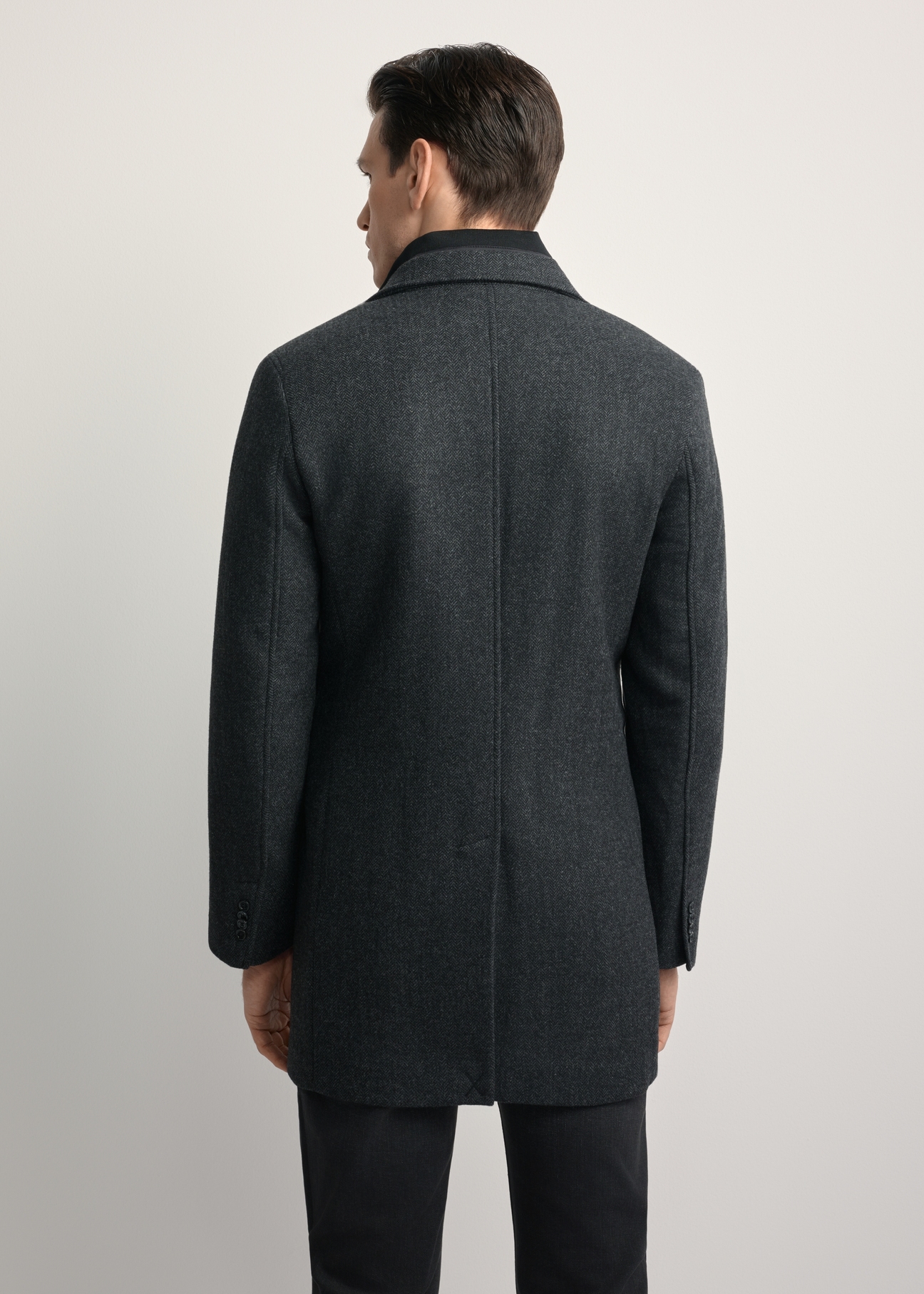 Pánsky vlnený kabát sivej farby PLAMT-0008-91(Z25), pohľad na modelku zozadu. Viditeľná polovica siluety.