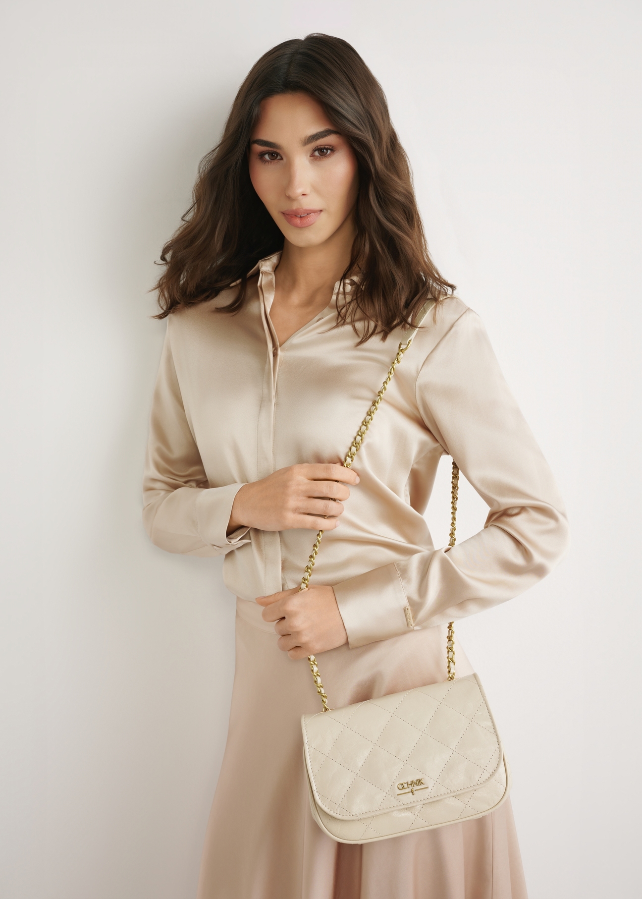 Dámska lakovaná kožená kabelka v krémovej farbe TORES-1297-0B(W26), pohľad spredu na produkt na modelke. Viditeľná silueta po kolená.