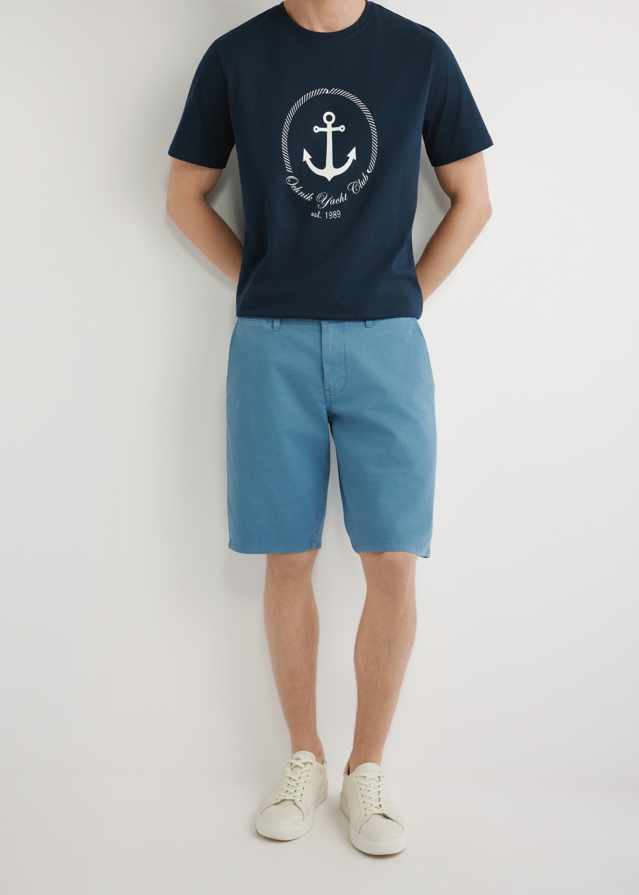 Pánske modré šortky SZOMT-0029-7B(W26), pohľad spredu na produkt na modelke. Viditeľná polovica siluety.