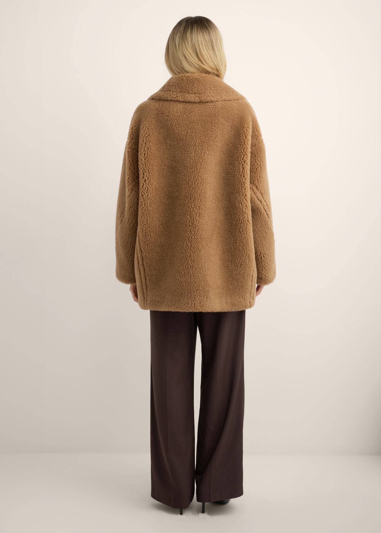 Dámsky kabát z ťavej kožušiny s vlnou FUTDW-0040-1D(Z26), pohľad na produkt zozadu na modelke. Viditeľné celé telo.