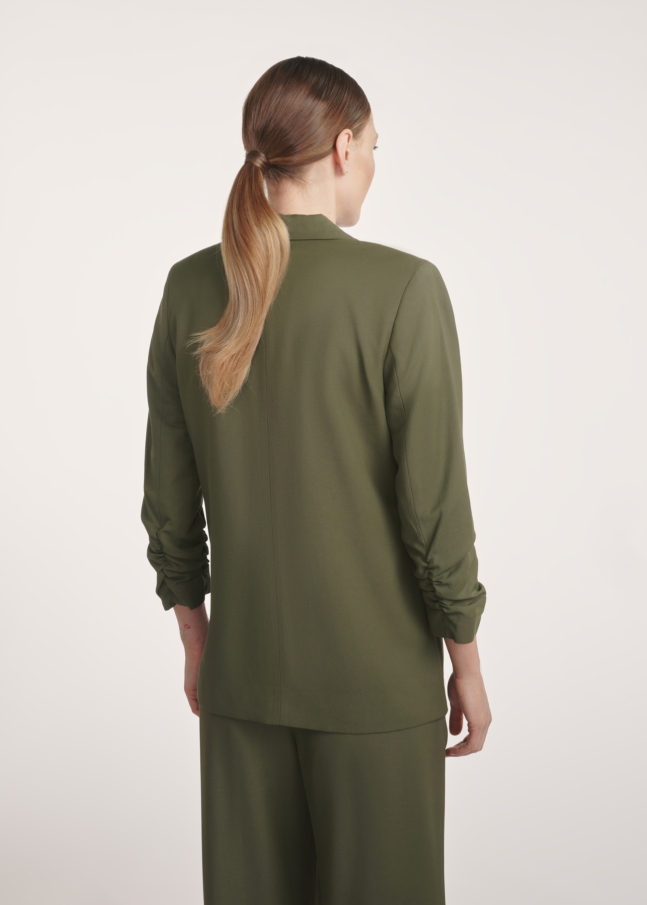 Dámske khaki sako ZAKDT-0043-55(Z25), pohľad na modelku zozadu. Viditeľná polovica siluety.