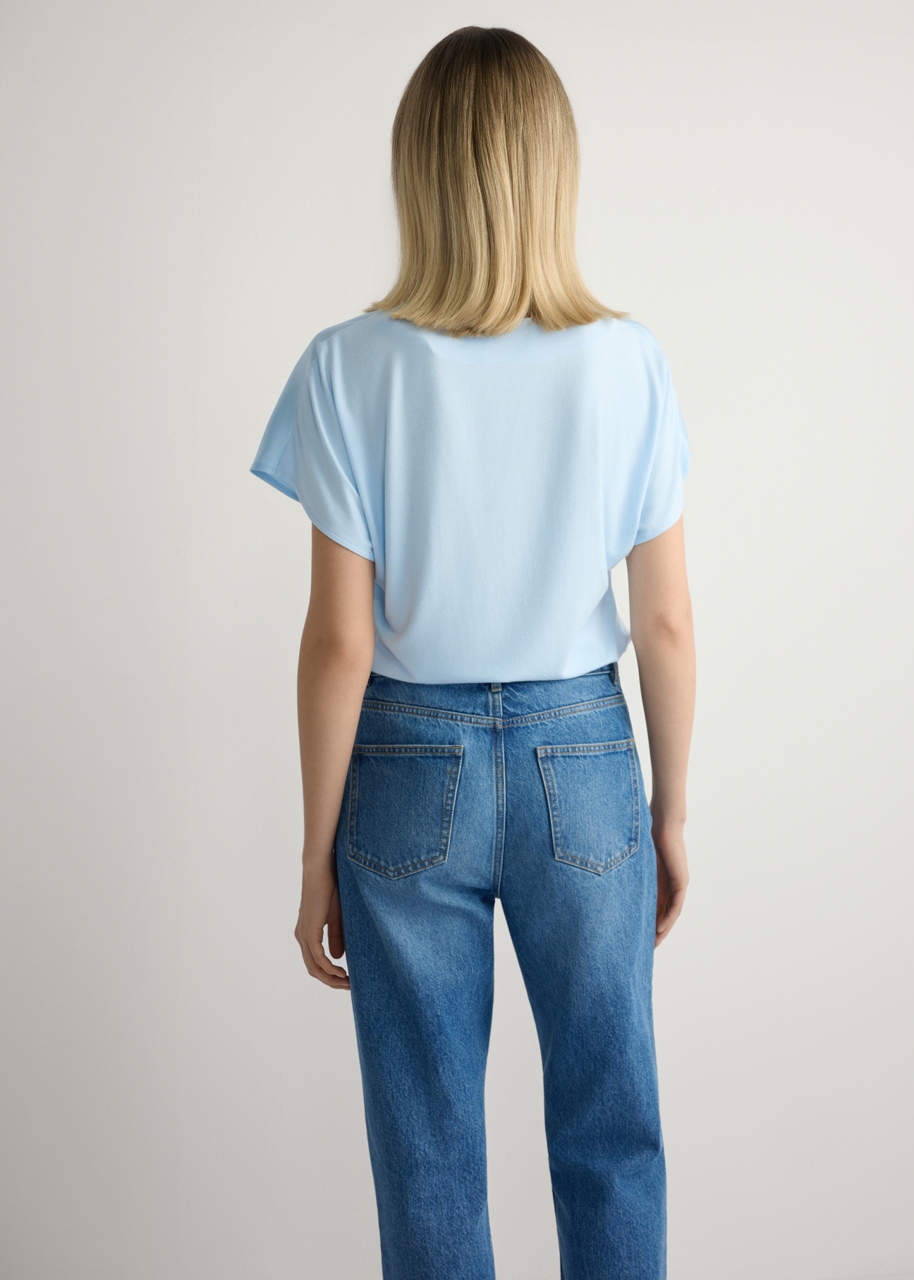 Svetlomodrá dámska blúzka BLUDT-0206-7A(W26), pohľad na modelku zozadu. Viditeľná polovica siluety.