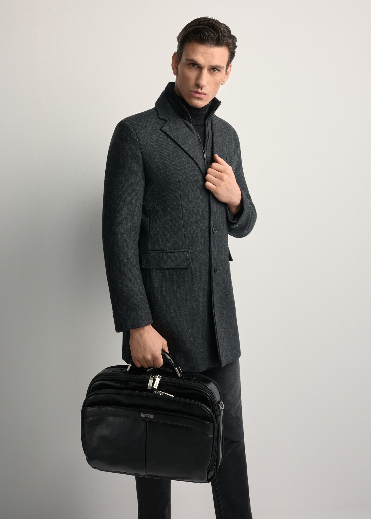 Čierna kožená pánska taška na notebook TORMS-0482-99(Z25) - pohľad spredu na produkt, ktorý drží model. Viditeľné celé telo.