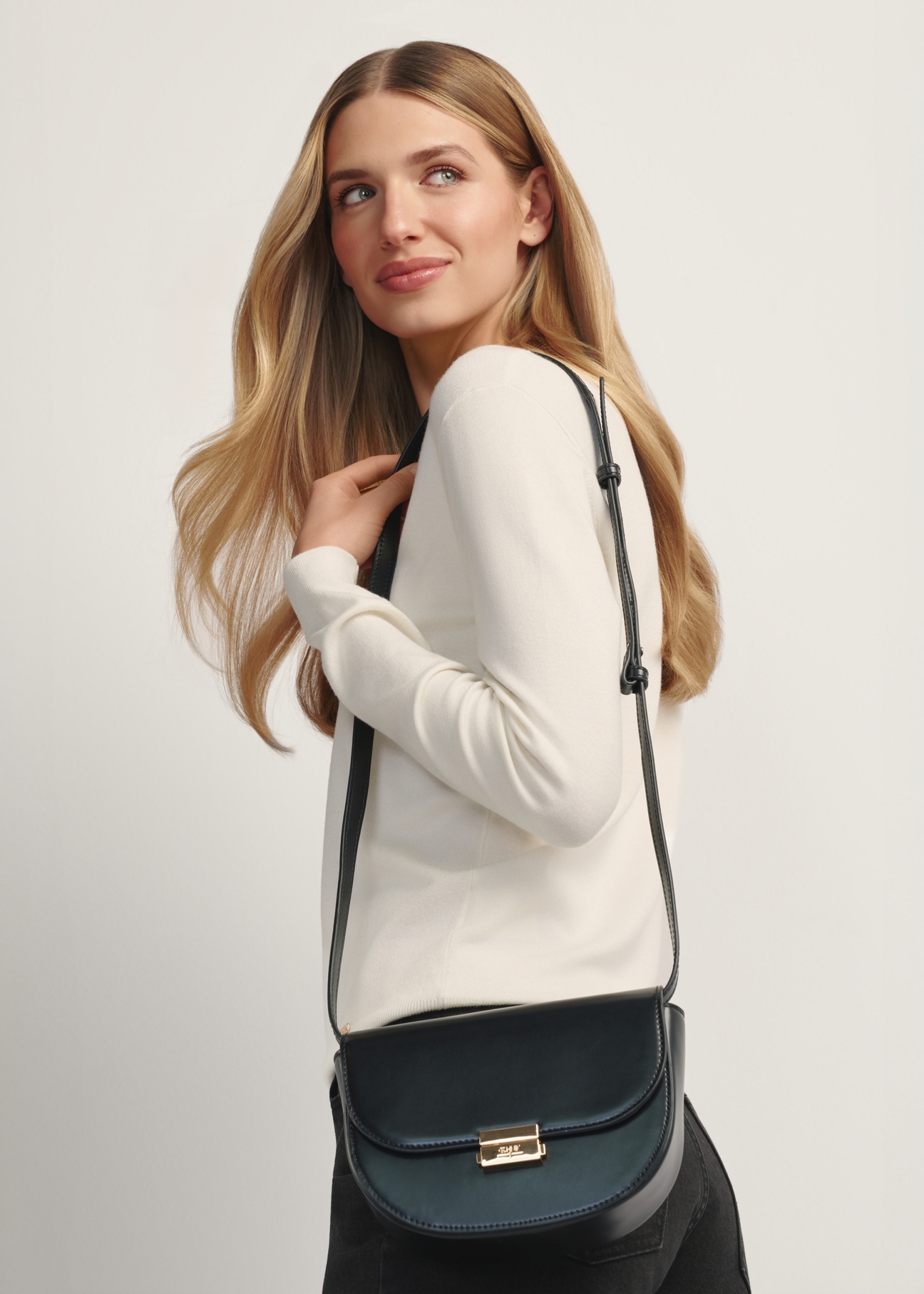 Čierna polkruhová dámska taška cez rameno TOREC-1127-99(W26), pohľad spredu na produkt na modelke, viditeľná polovica siluety.