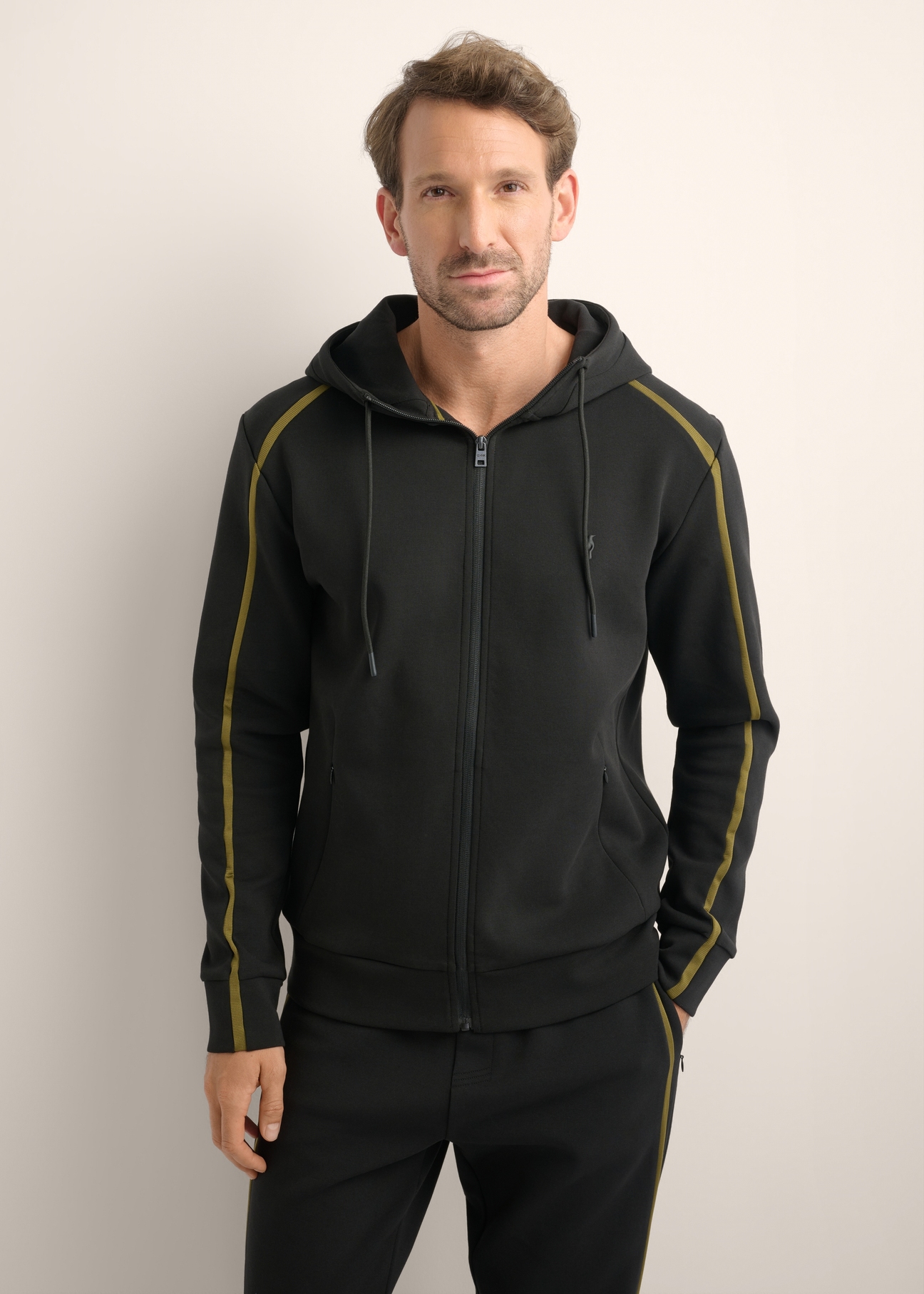 Pánska čierna mikina na zips BLZMT-0083-99(Z26), pohľad spredu na produkt na modelke. Viditeľná polovica siluety.