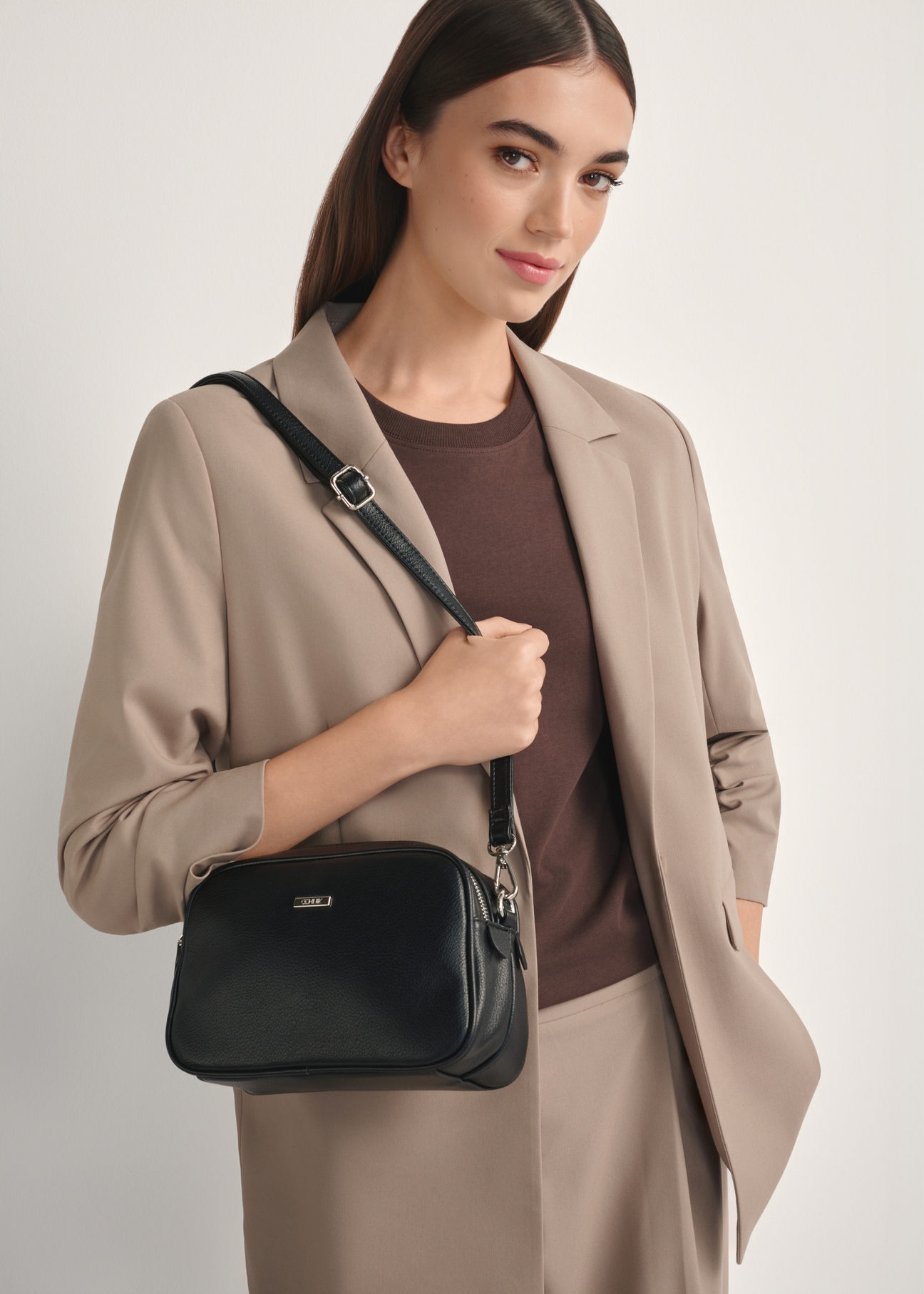 Čierna stredne veľká dámska kabelka TOREC-1121-9I(W26), pohľad spredu na produkt na modelke, viditeľná polovica siluety.