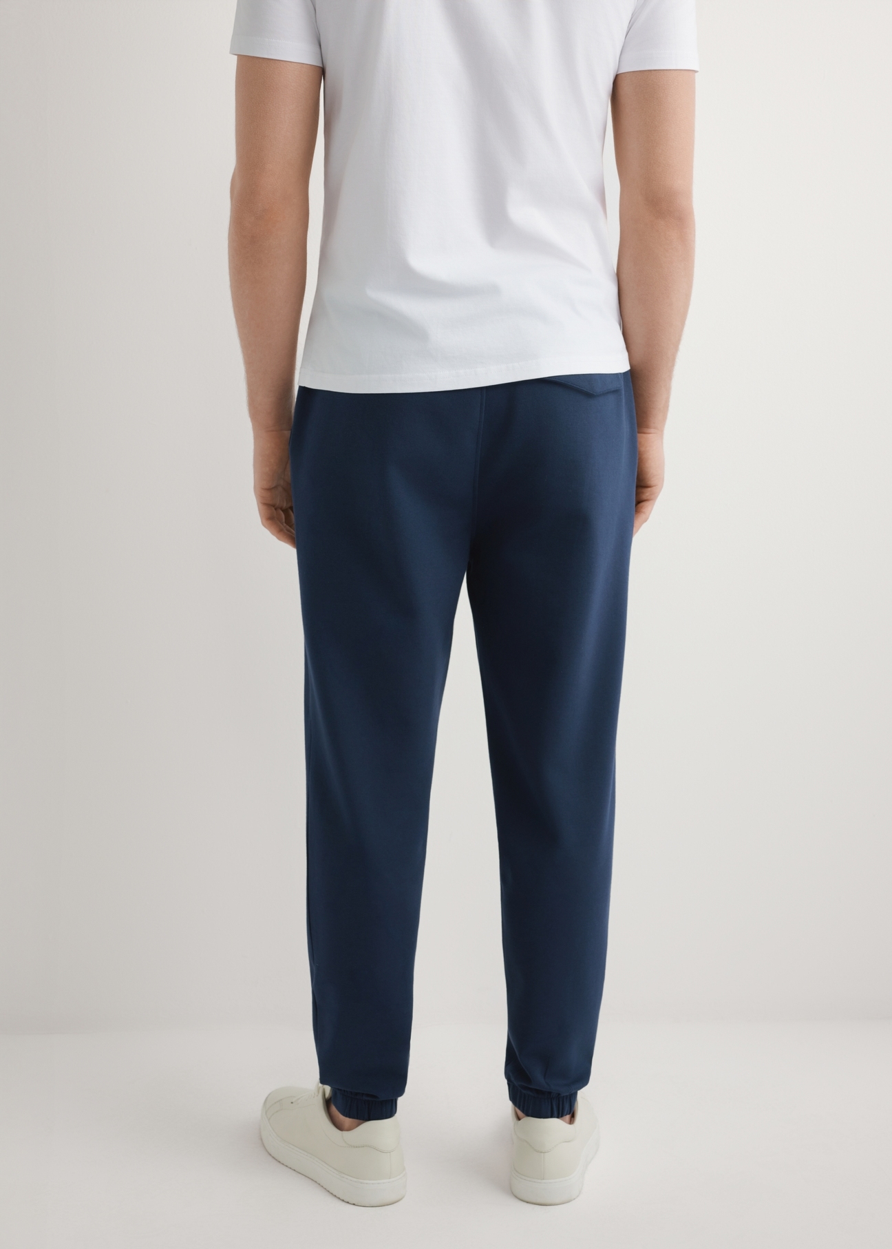 Pánske tmavomodré tepláky SPOMT-0109-7E(W26), pohľad na produkt zozadu na modeli. Viditeľná polovica siluety.