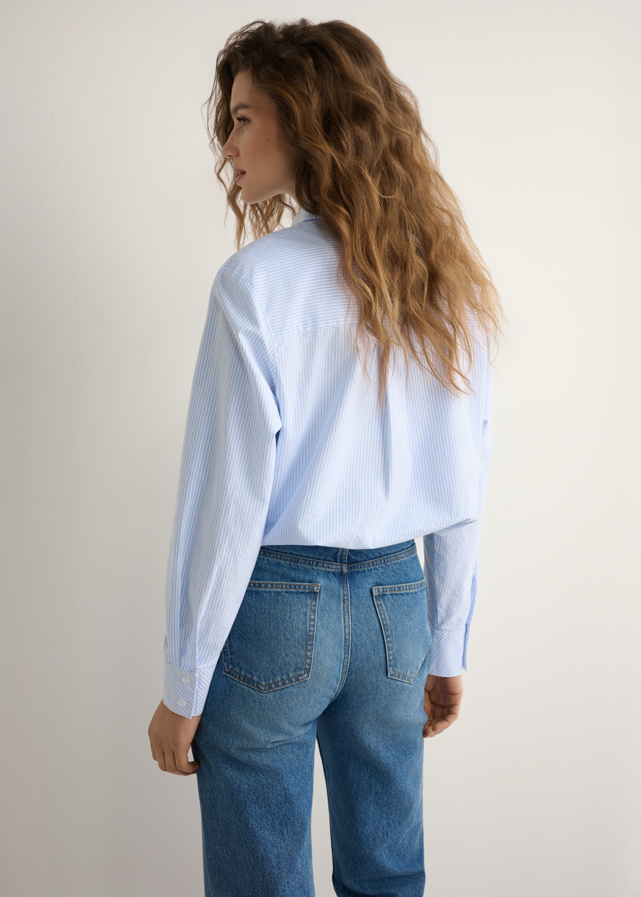 Dámska pruhovaná bavlnená košeľa KOSDT-0184-7A(W26), pohľad na produkt zozadu na modelke. Viditeľná polovica siluety.