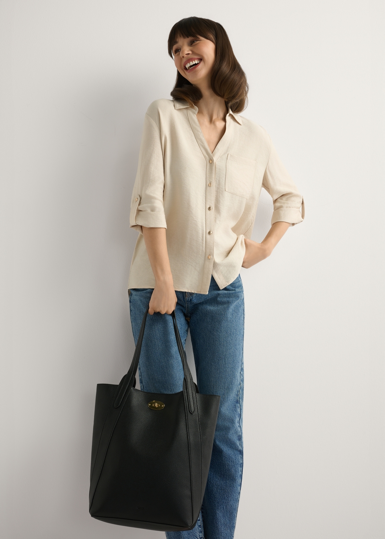 Veľká čierna dámska nákupná kabelka TOREC-1142-9I(W26), pohľad na produkt v ruke modelky. Viditeľné celé telo.