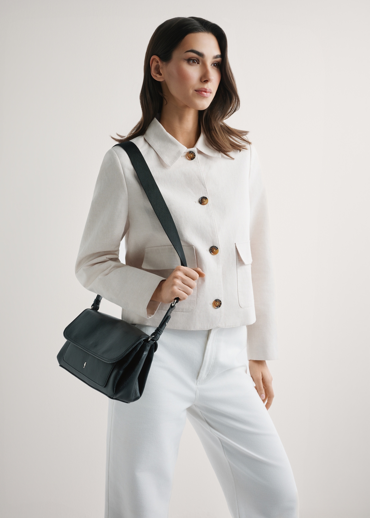 Klasická čierna dámska kabelka TOREC-1124-99(W26), pohľad na produkt na ramene modelky. Viditeľná polovica siluety.