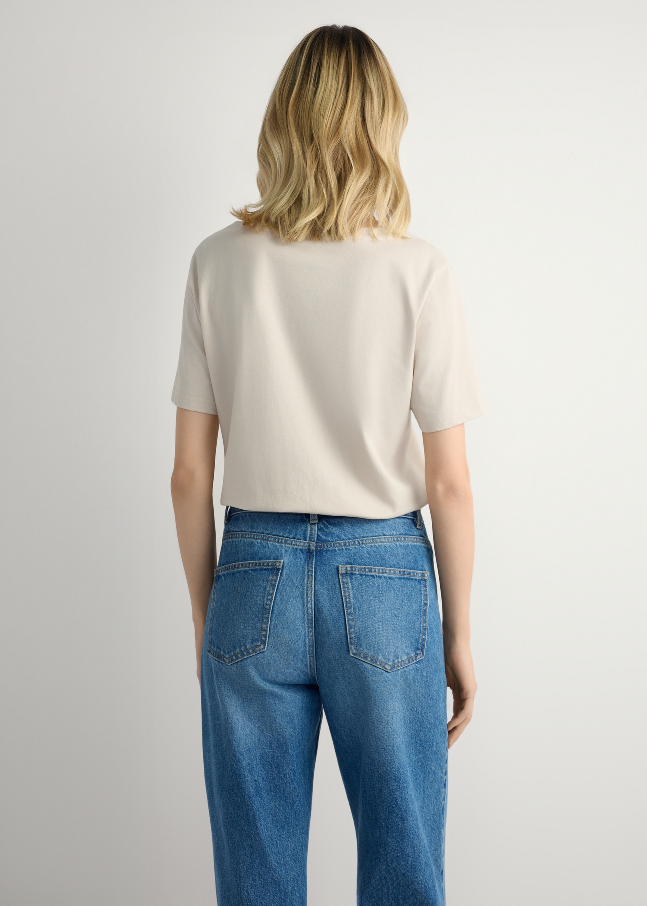 Svetlobéžové dámske tričko TSHDT-0120-1A(W26), pohľad na produkt zozadu na modelke. Viditeľná polovica siluety.