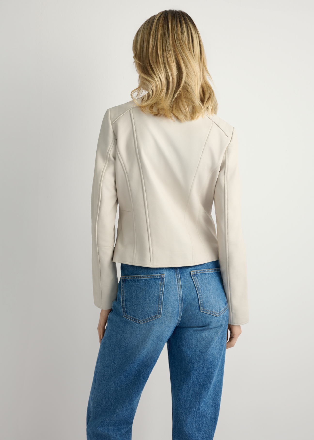 Dámska béžová kožená bunda KURDS-0603-0B(W26) - Pohľad na výrobok zozadu, na modelke, na svetlom pozadí. Viditeľná silueta po kolená.