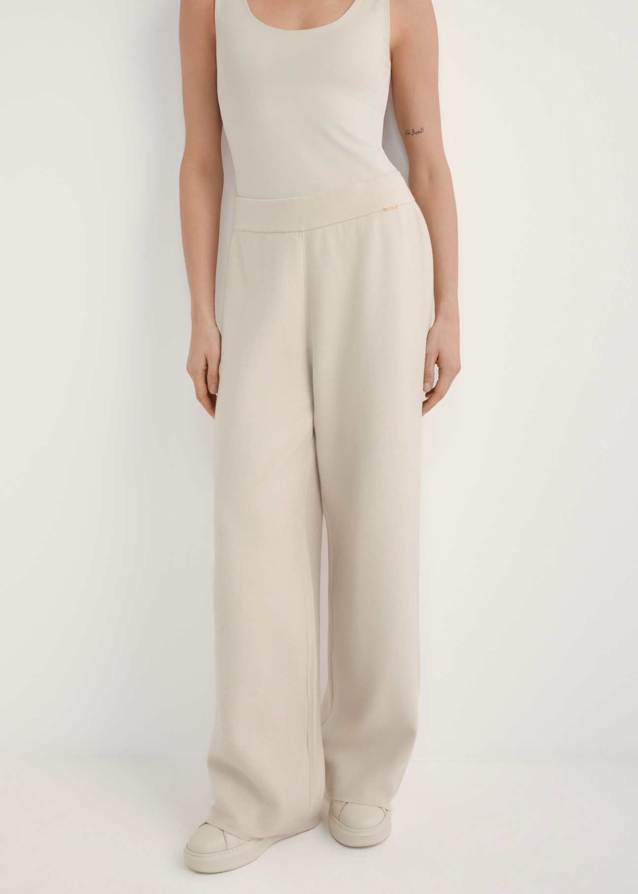 Béžové dámske nohavice so širokými nohavicami SPODT-0121-1A(W26), pohľad spredu na produkt na modelke. Viditeľná polovica siluety.