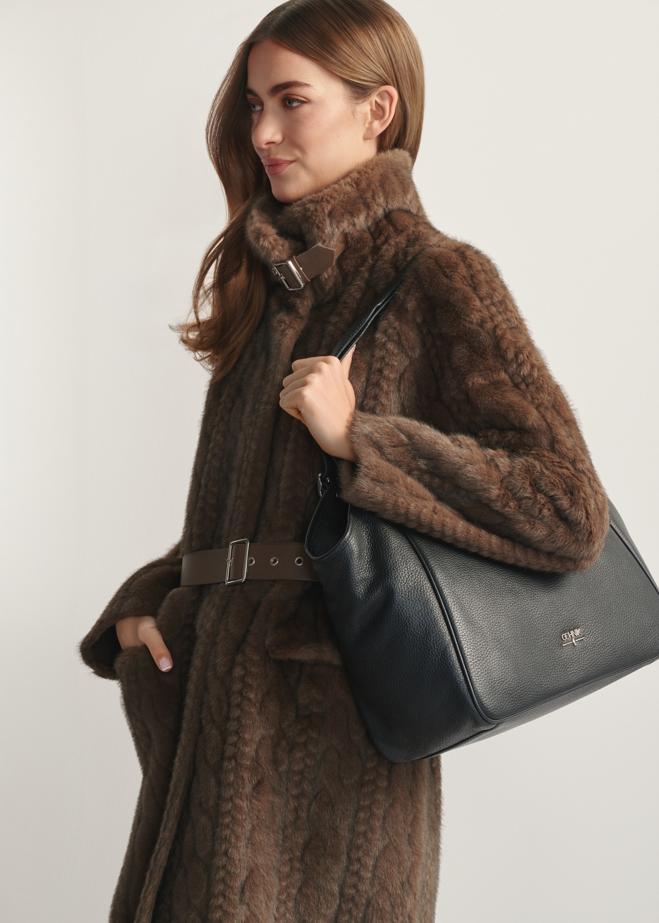 Veľká čierna kožená dámska kabelka TORES-1042D-99(Z25) - bočný pohľad na produkt, na modeli, na svetlom pozadí. Viditeľná polovica siluety.