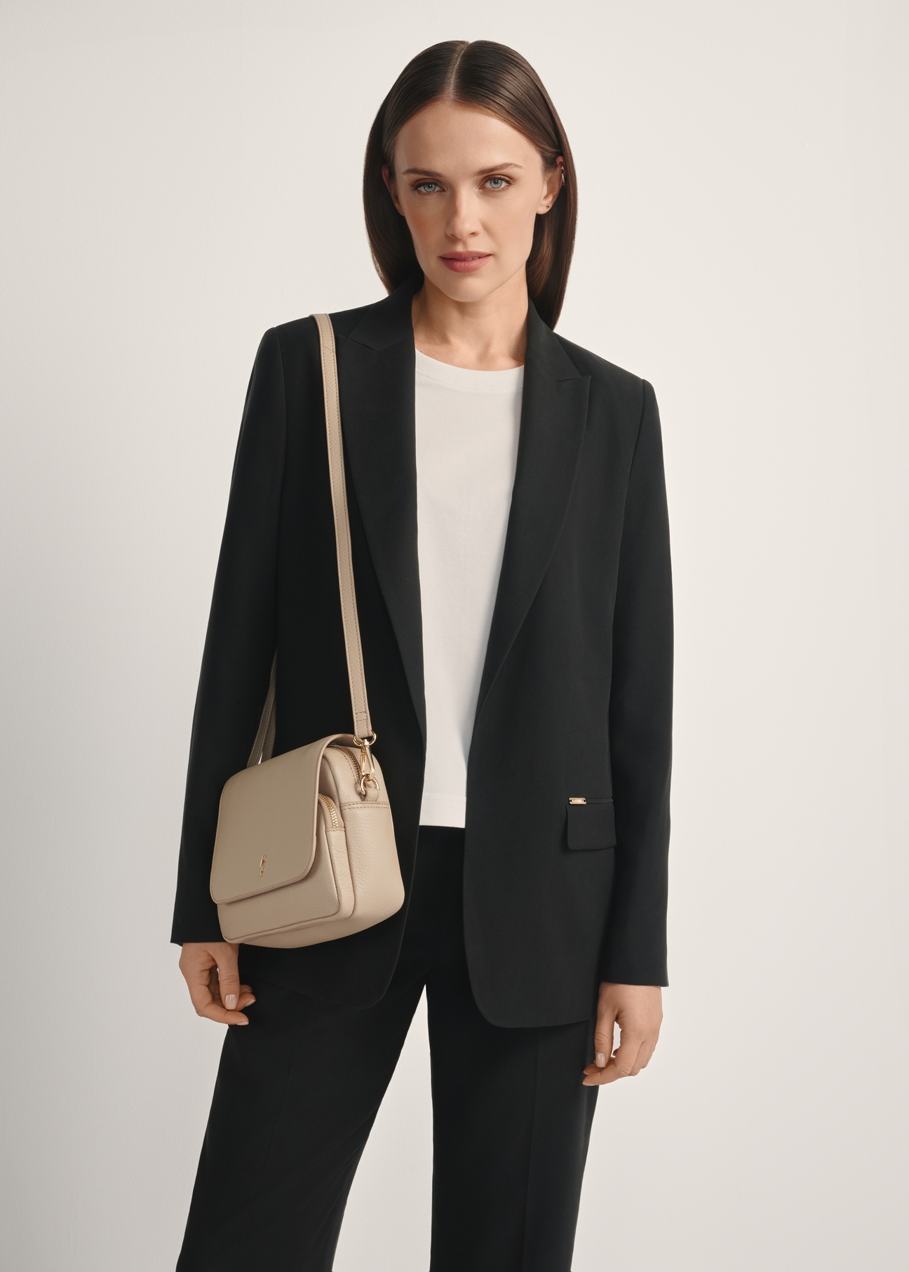 Dámska kožená kabelka cez rameno béžovej farby TORES-0958E-1B(W26), diagonálny pohľad na produkt na modelke, viditeľná polovica siluety.