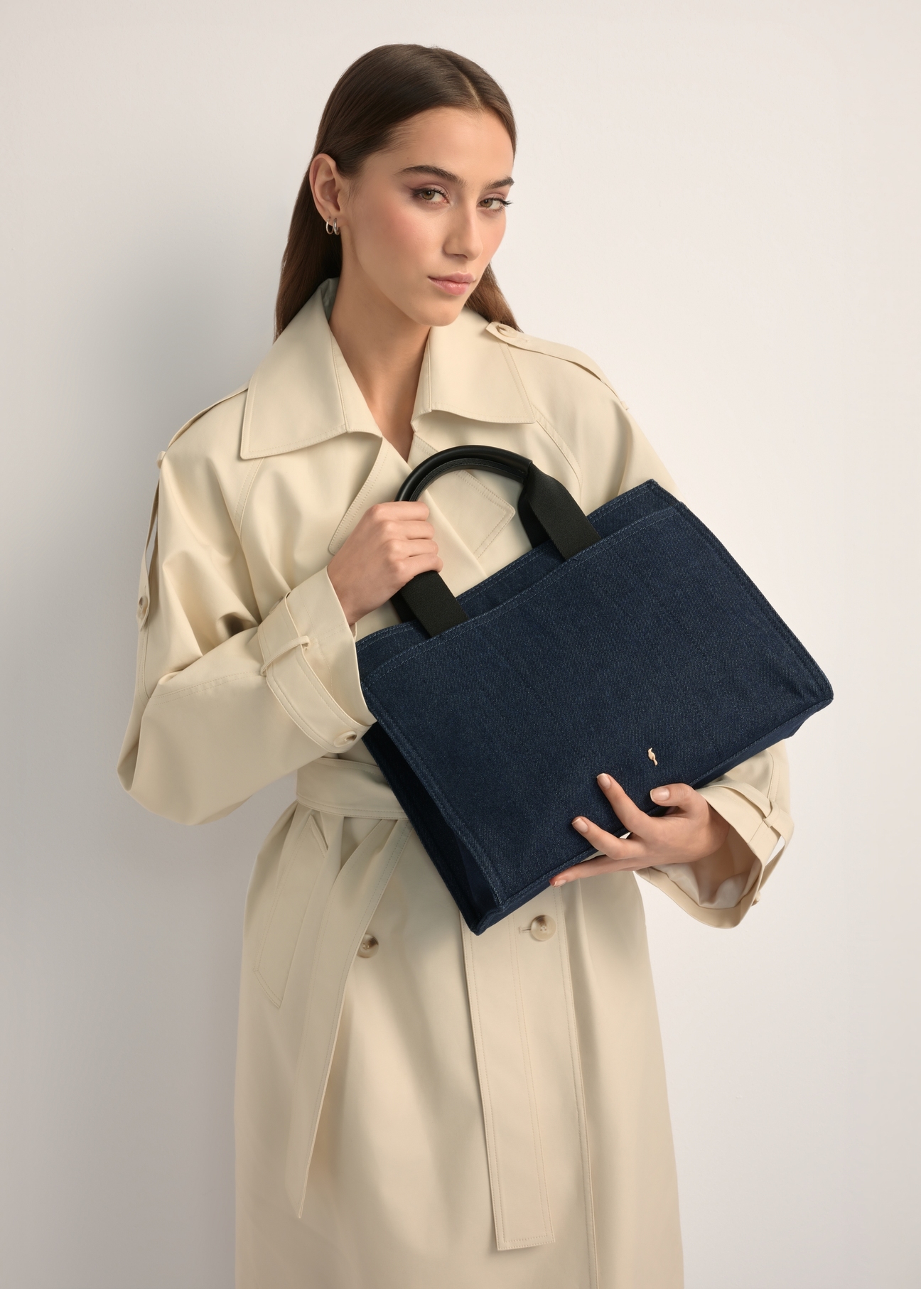 Dámska džínsová kabelka TOREN-0332-7H(W26) v tmavomodrej farbe, pohľad na produkt v rukách modelky. Viditeľná polovica siluety.