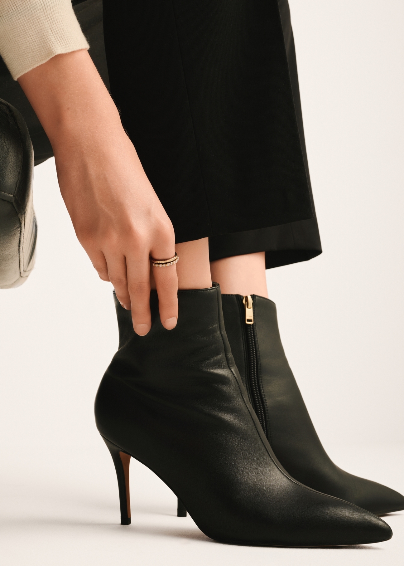 Čierne kožené členkové čižmy na vysokom podpätku BUTYD-1122-99(Z25), pohľad na produkt na nohách modelky na svetlom pozadí.