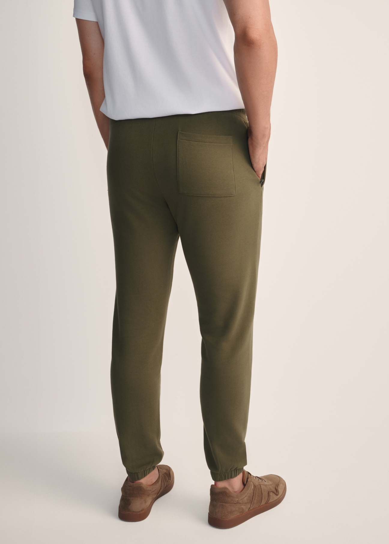 Pánske khaki tepláky SPOMT-0101-55(Z25), pohľad na modelku zozadu. Viditeľná polovica siluety.