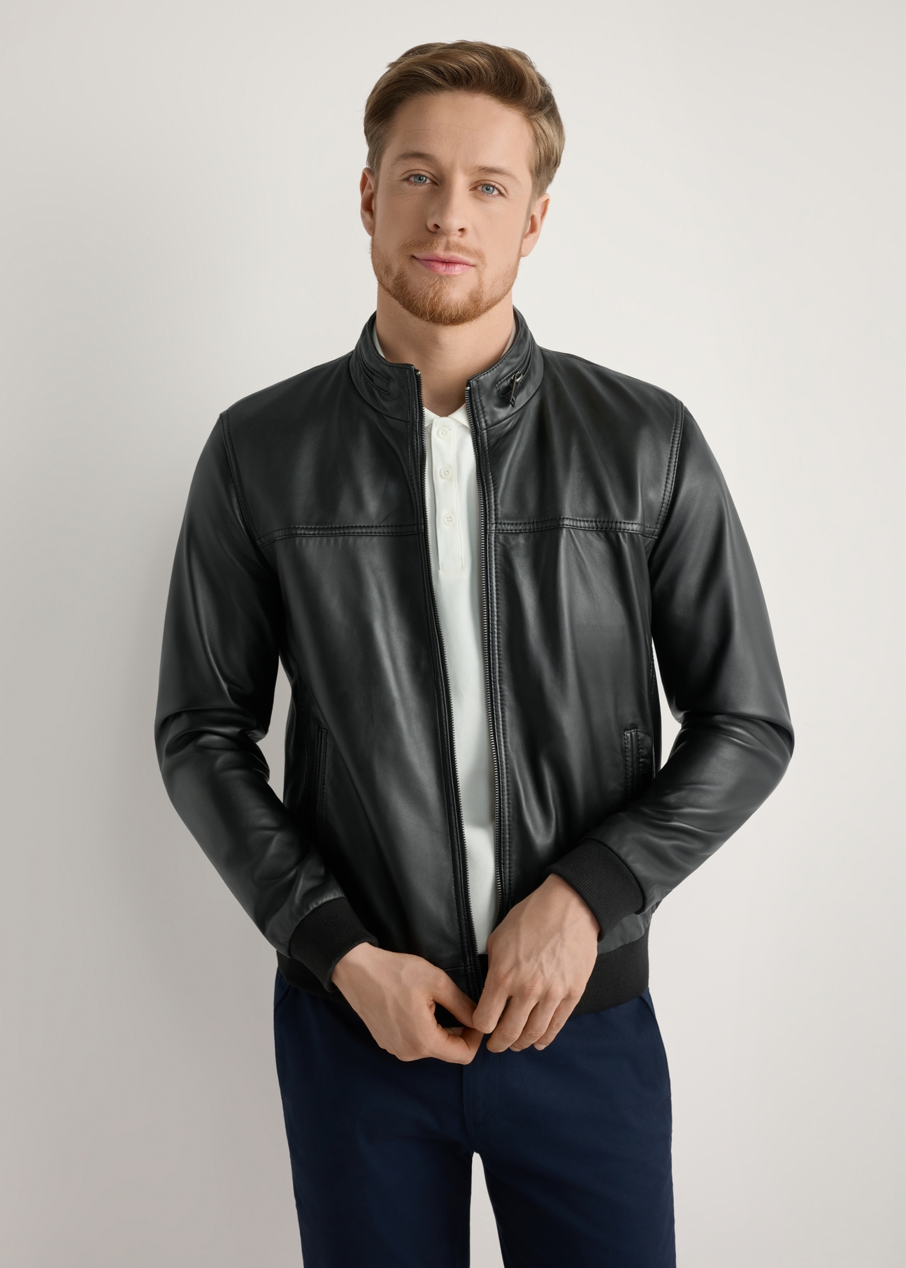 Pánska čierna kožená bunda KURMS-0392-99(W26) - pohľad spredu na produkt, na modelke, na svetlom pozadí. Viditeľná polovica siluety.