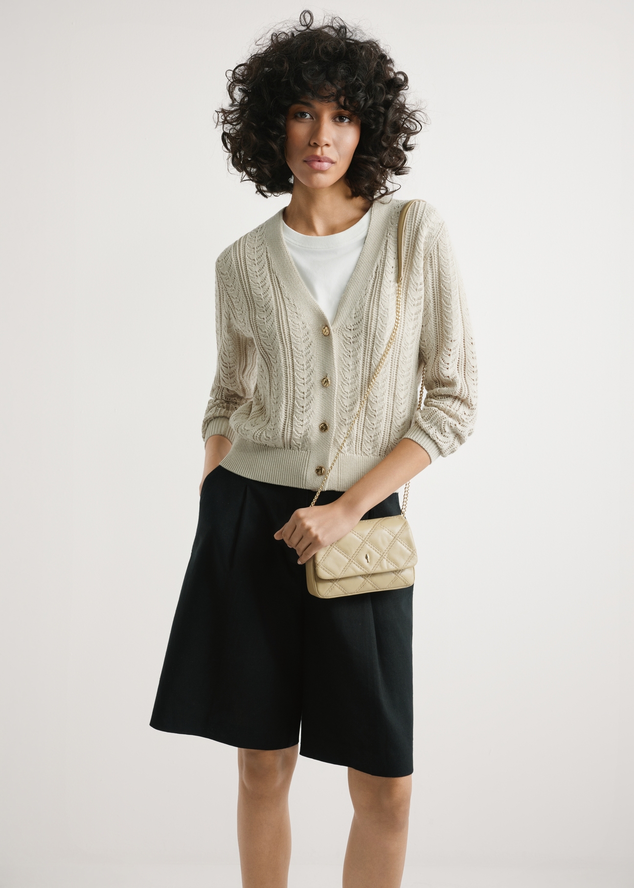 Malá béžová dámska kožená kabelka TORES-1044-1B(W26) - pohľad spredu na produkt, na modelke, na svetlom pozadí. Viditeľná silueta po polovičnú dĺžku.