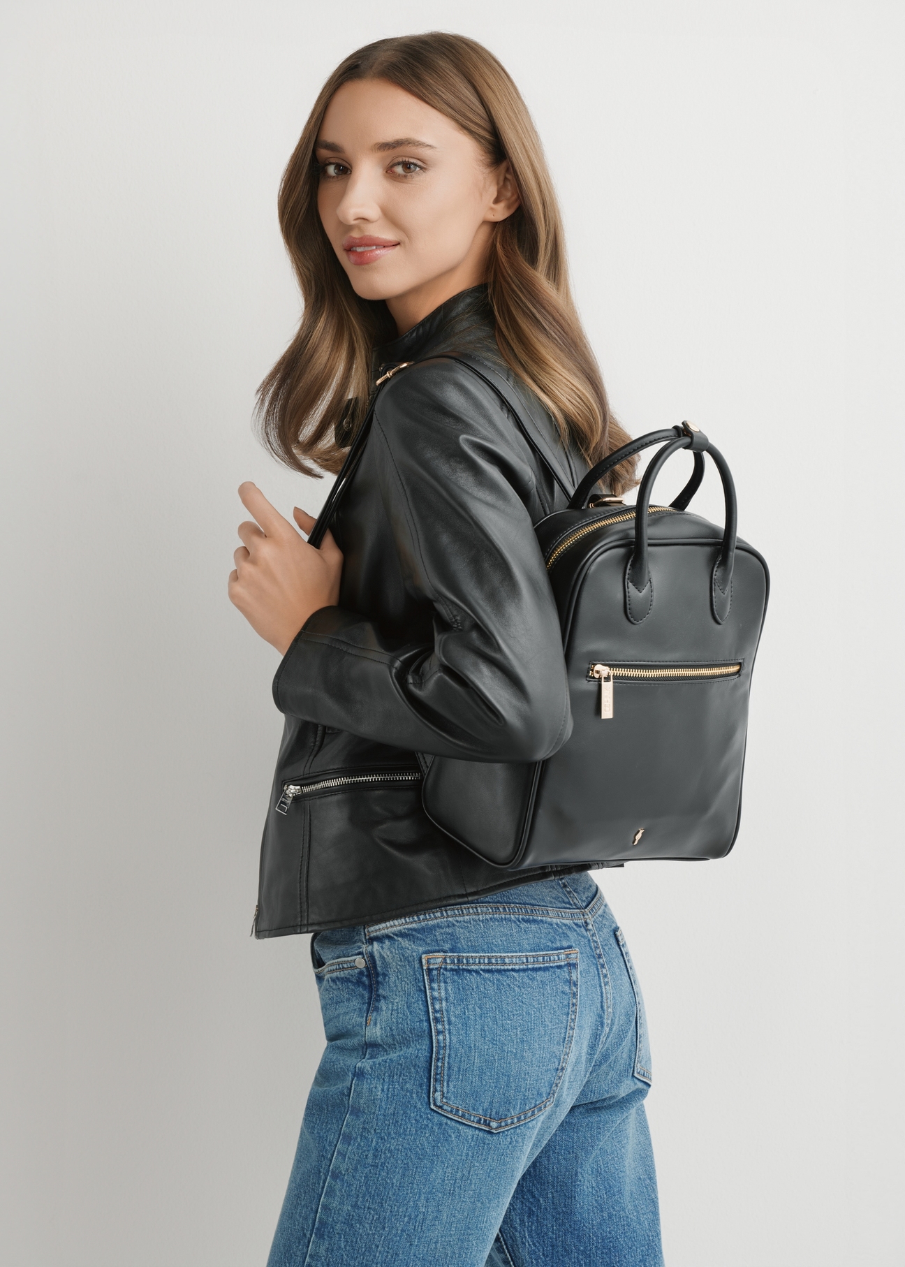 Dámsky koženkový batoh TOREC-1129-99(W26), čierny, pohľad na produkt na ramene modelky. Viditeľná polovičná silueta.