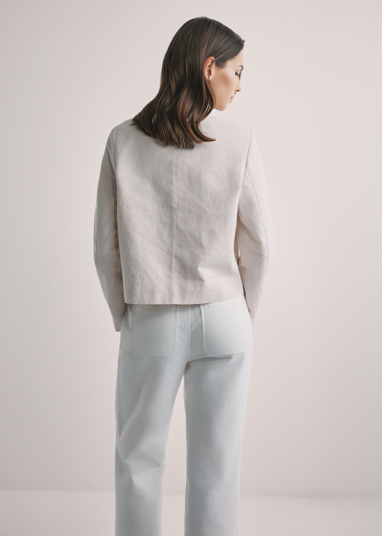 Svetlobéžová dámska ľanová bunda KURDT-0652-1A(W26), pohľad zozadu na modelku. Viditeľná polovica siluety.