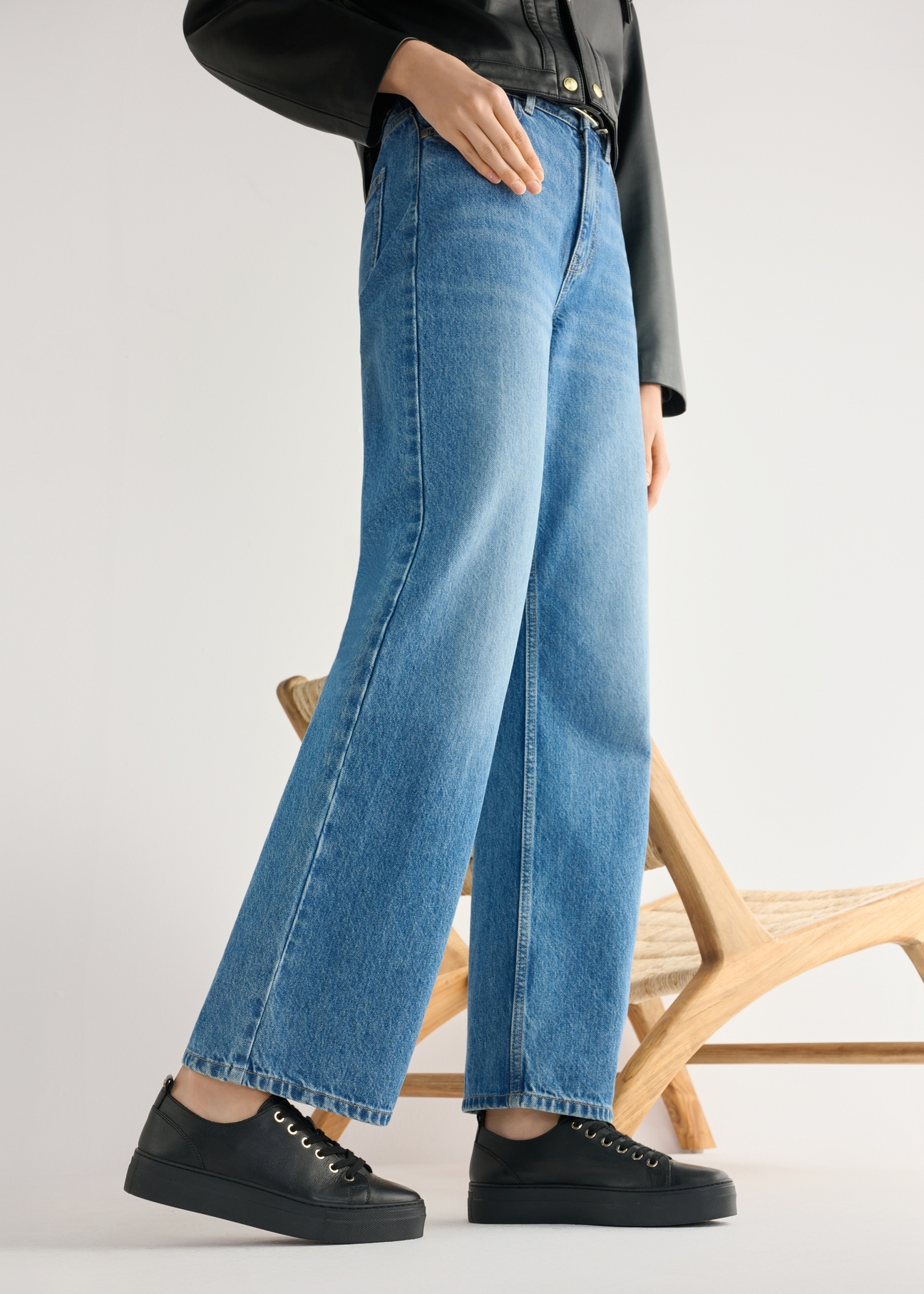 Dámske čierne kožené tenisky BUTYD-1062-99(W26) - bočný pohľad na produkt, na modelke, na svetlom pozadí. Viditeľná silueta po kolená.