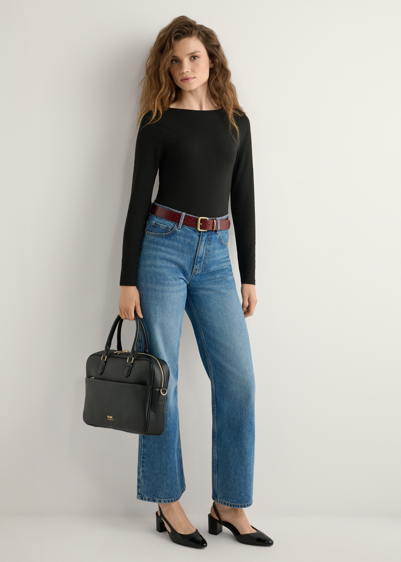 Čierna dámska taška na notebook TOREC-1209-99(W26), pohľad na produkt v ruke modelky. Viditeľné celé telo.