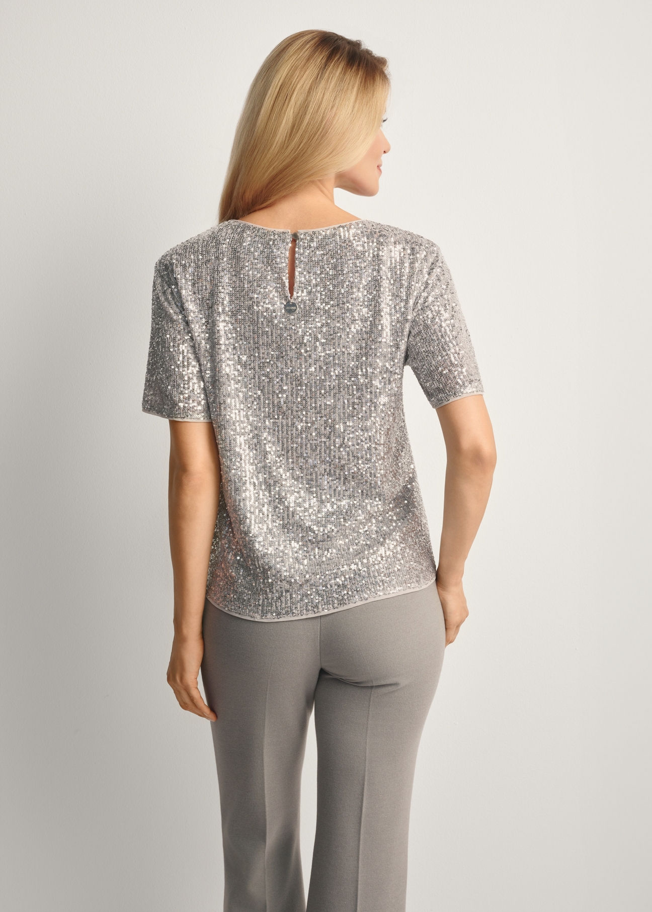 Dámska strieborná flitrovaná blúzka BLUDT-0199-92(Z25), pohľad na produkt zozadu na modelke, viditeľná polovica siluety.