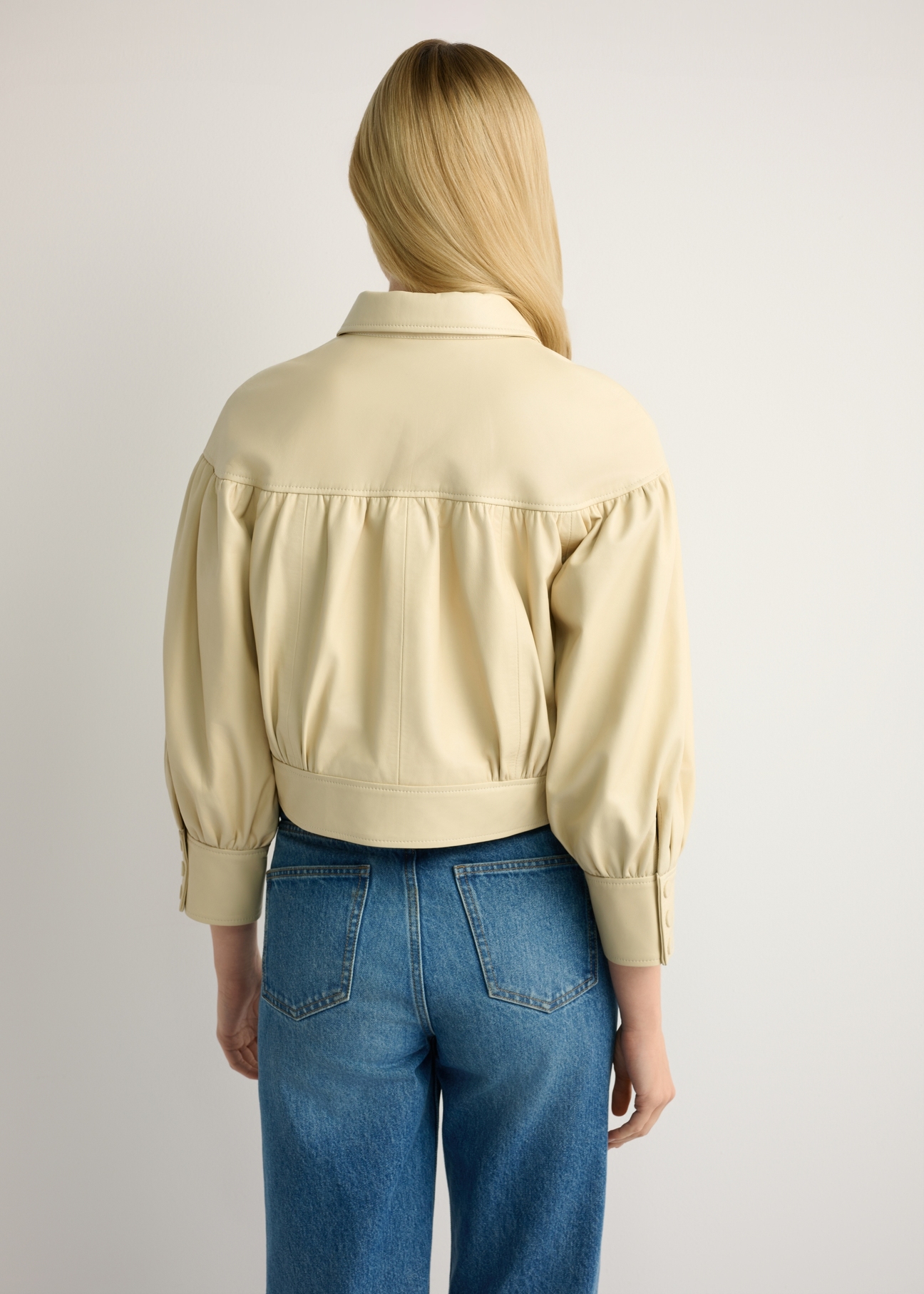 Svetložltá dámska kožená bunda KURDS-0574-2A(W26), pohľad zozadu na modelku. Viditeľná polovica siluety.