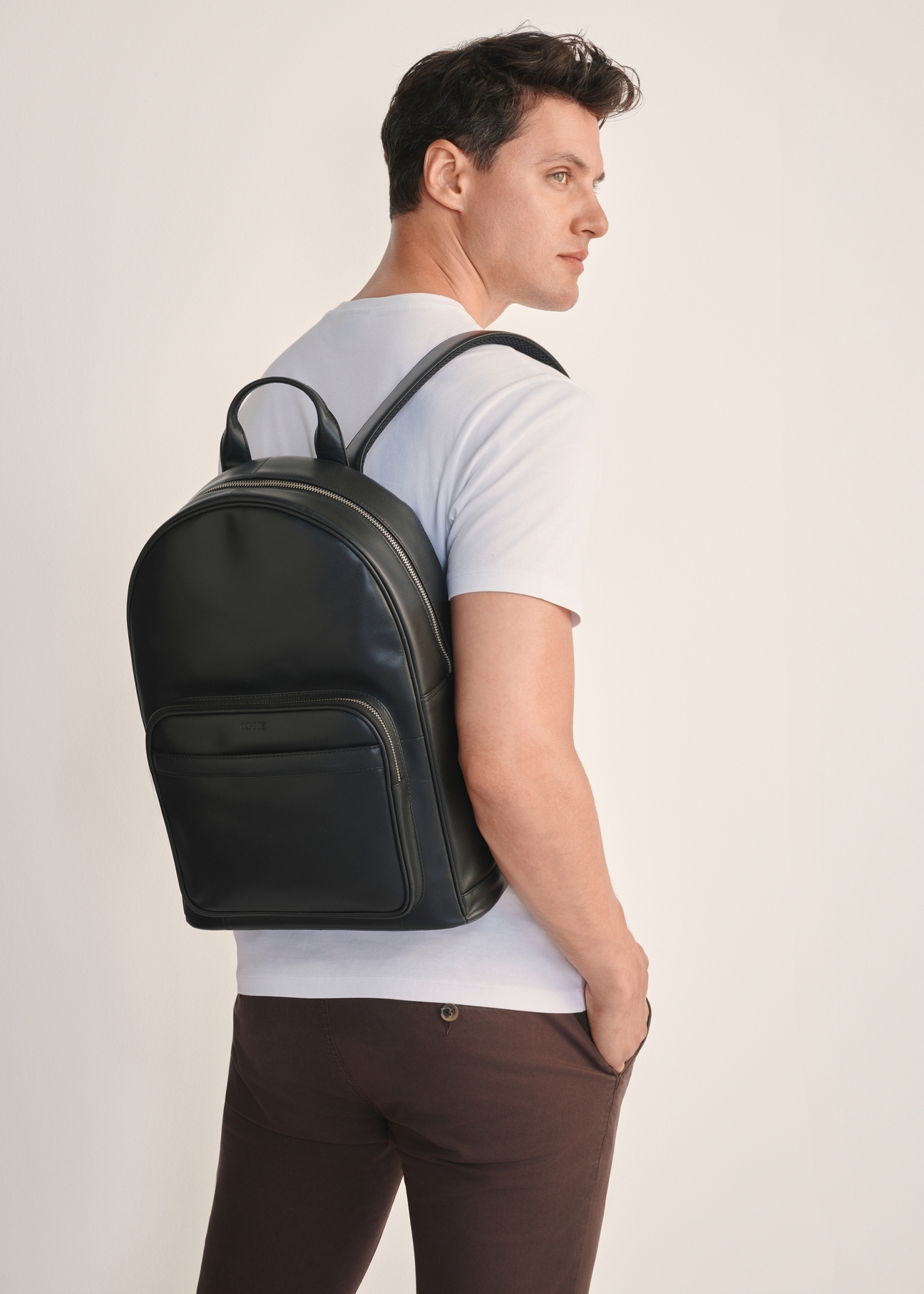 Čierny pánsky kožený batoh TORMS-0472-99(Z25), pohľad na produkt spredu na modeli, viditeľná polovica siluety.
