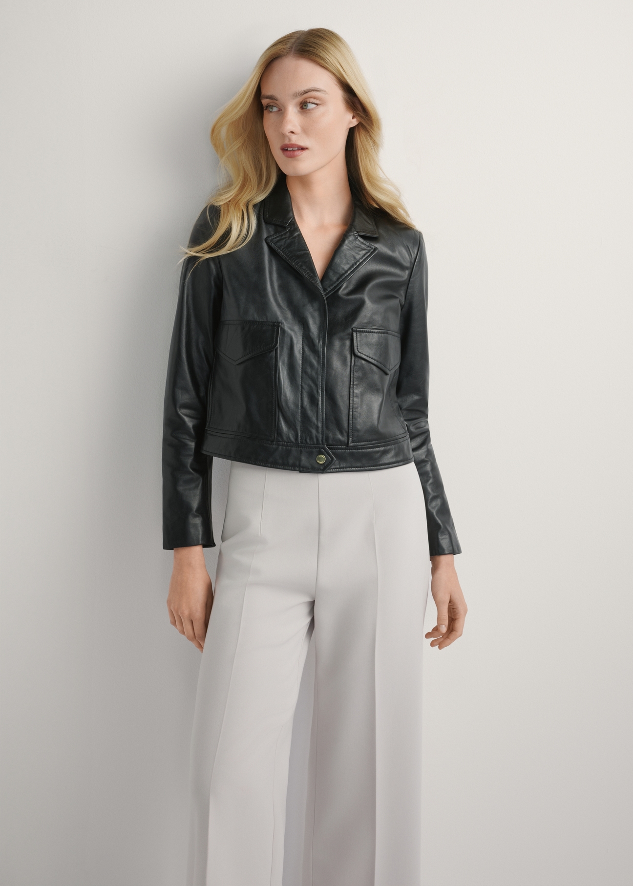 Dámska čierna kožená krátka bunda KURDS-0471-99(W26), pohľad spredu na produkt na modelke. Viditeľná polovica siluety.