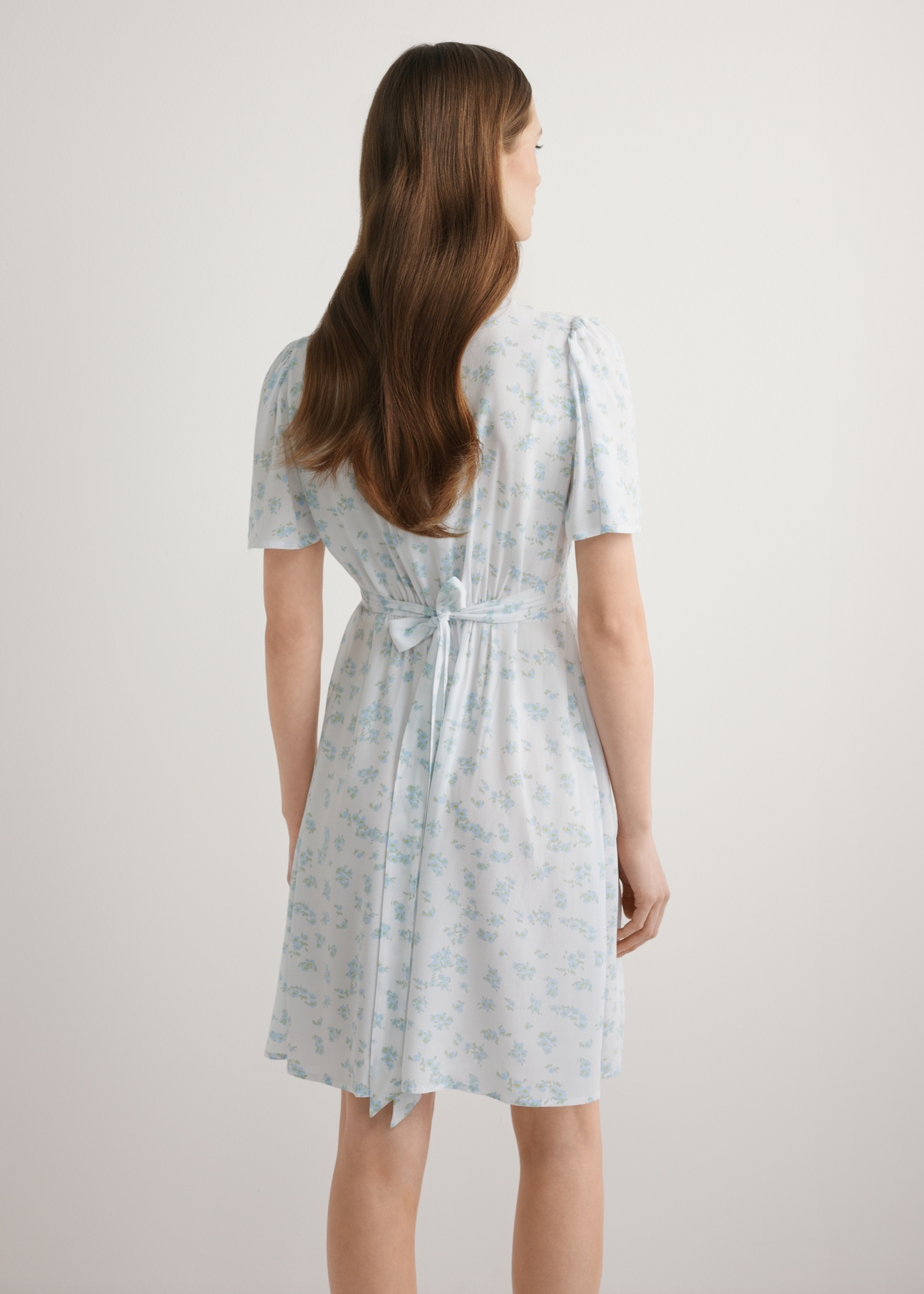 Dámske krátke kvetinové šaty SUKDT-0276-7P(W26), pohľad na modelku zozadu. Viditeľná polovica siluety.