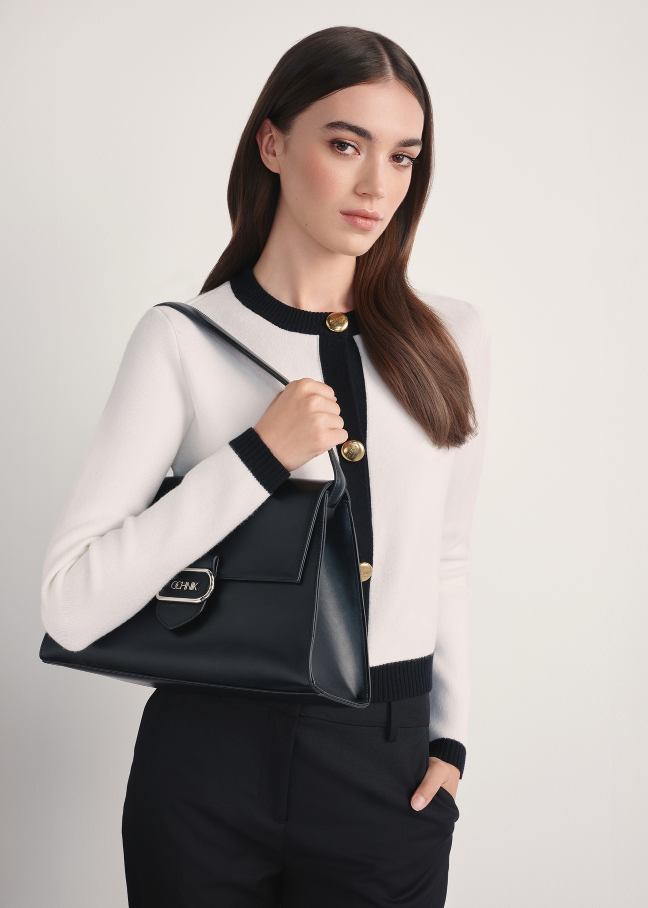 Elegantná čierna dámska kabelka TOREC-1068-99(Z25) - diagonálny pohľad na produkt na modeli, na bielom pozadí. Z boku je viditeľná polovica siluety.