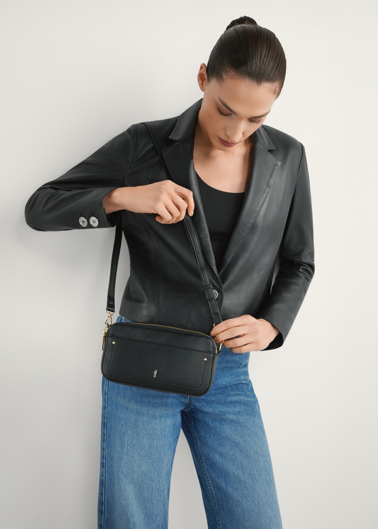 Malá čierna dámska kabelka TOREC-1173-99(W26), pohľad na produkt na ramene modelky. Viditeľná polovica siluety.