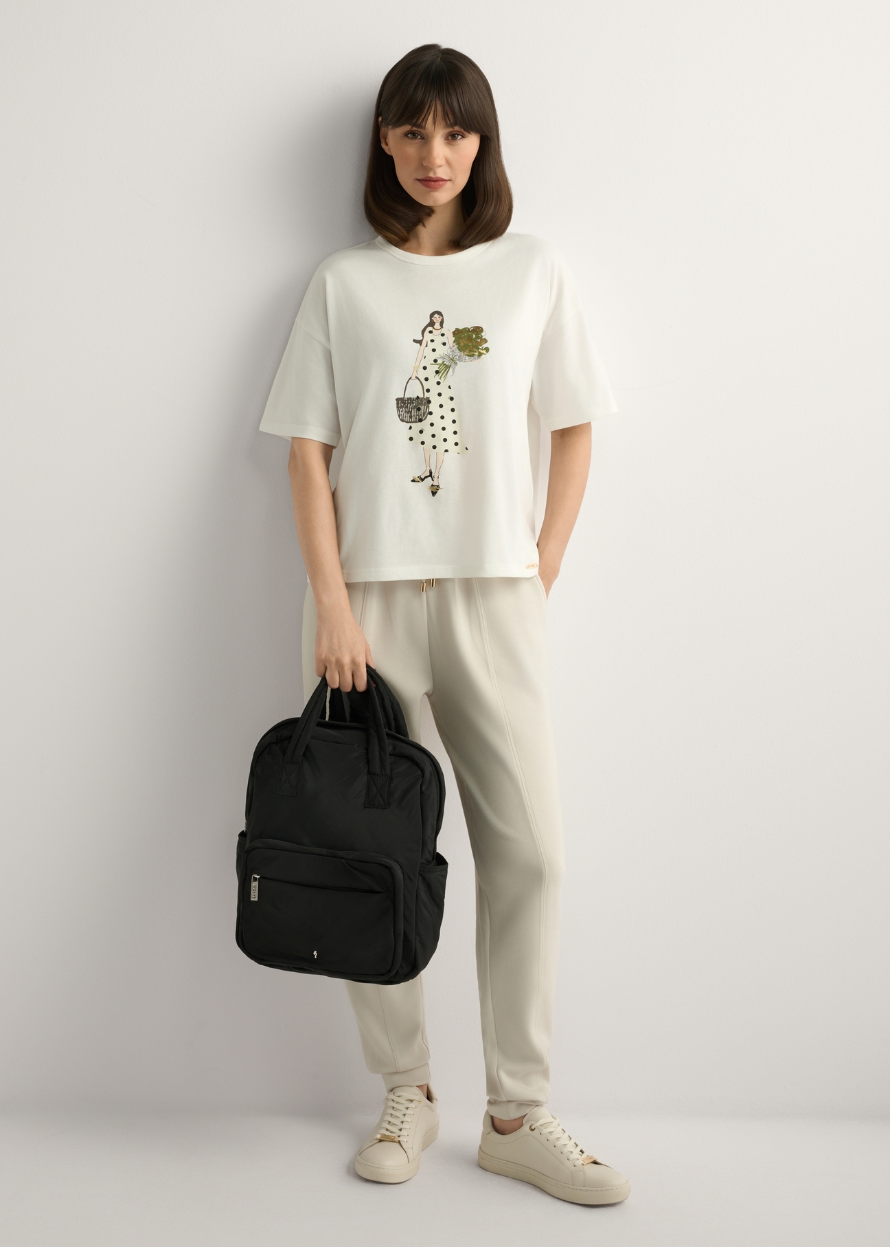 Čierny nylonový dámsky batoh TOREN-0341-99(W26), pohľad na produkt v ruke modelky. Viditeľné celé telo.